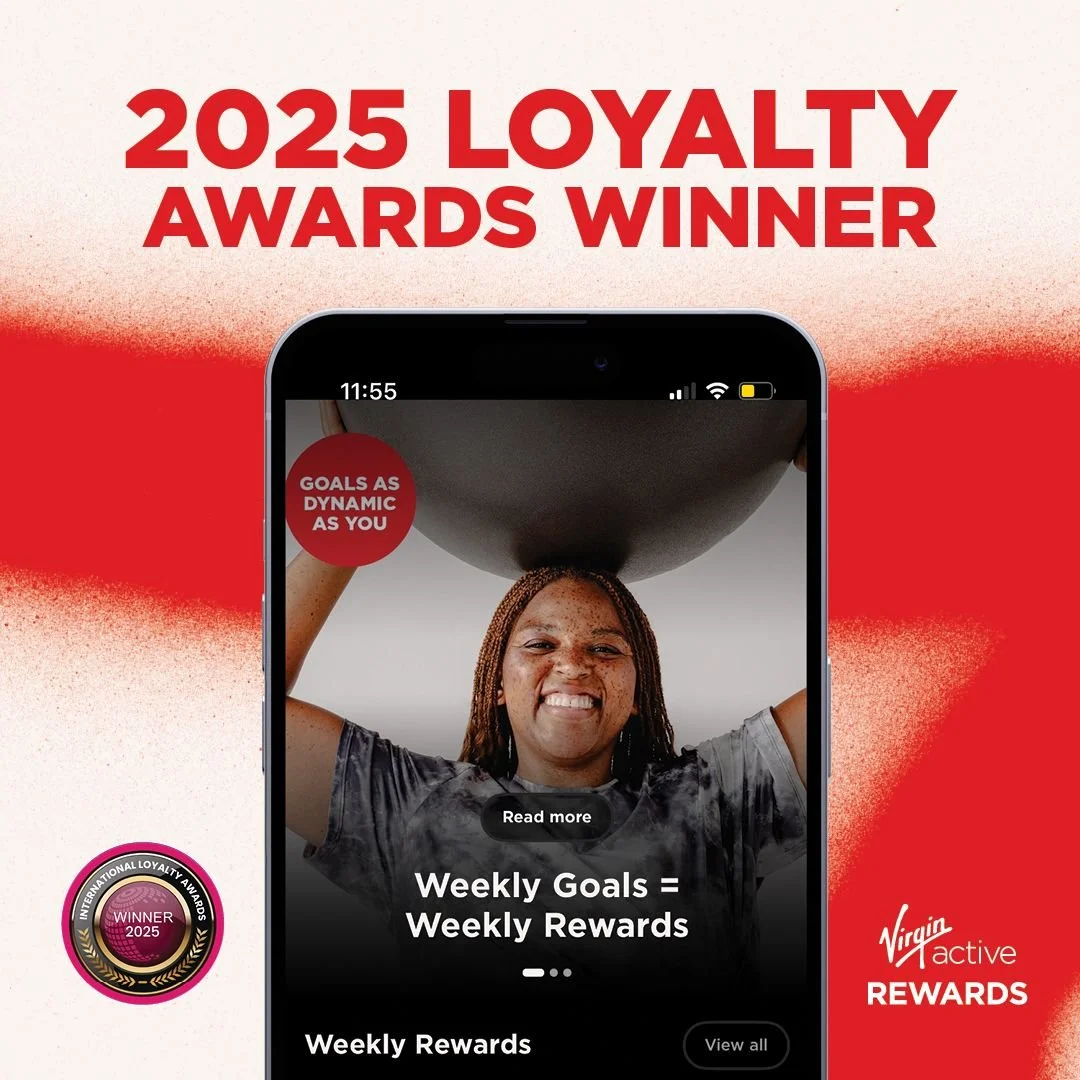 An advertisement for the Virgin Active Rewards loyalty program showing a woman lifting a weight. The text highlights that Virgin Active Rewards is a 2025 Loyalty Awards Winner, with slogans like "Goals as dynamic as you" and "Weekly Goals = Weekly Rewards."