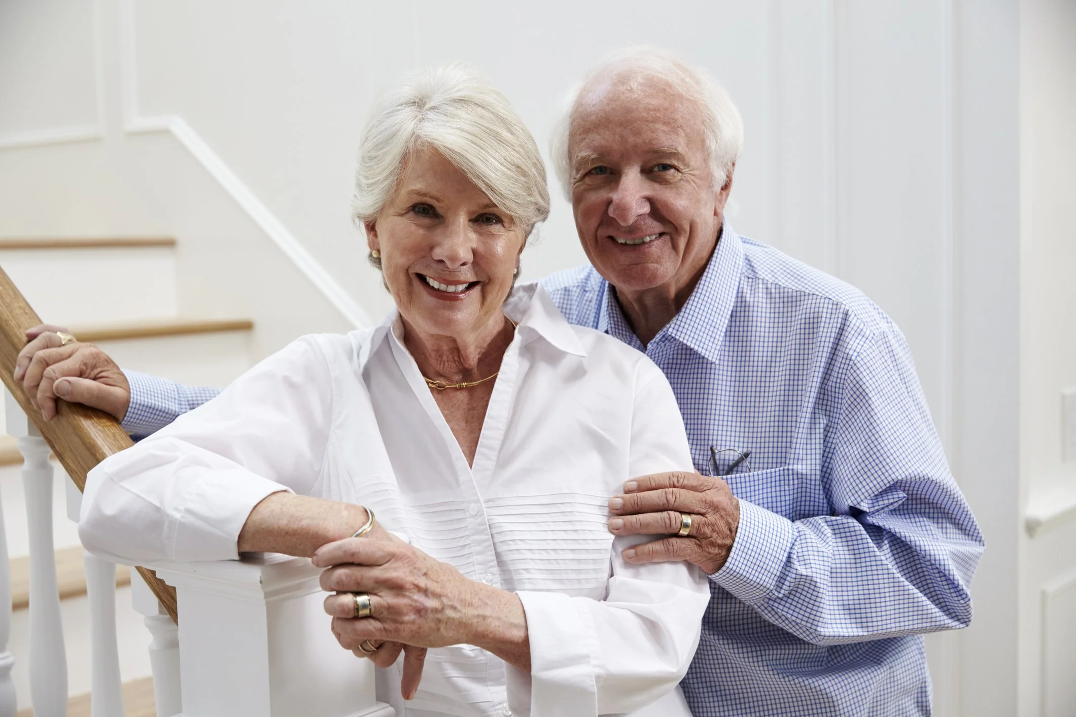 portrait-of-senior-couple-standing-by-staircase-at-home-864938854615.jpg