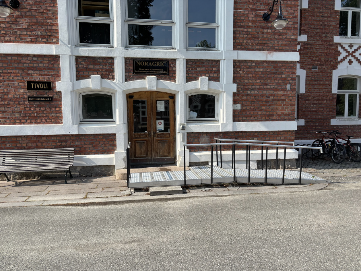 Provisorisk aluminiumsrampe foran inngangsdøren til et fredet murbygg.