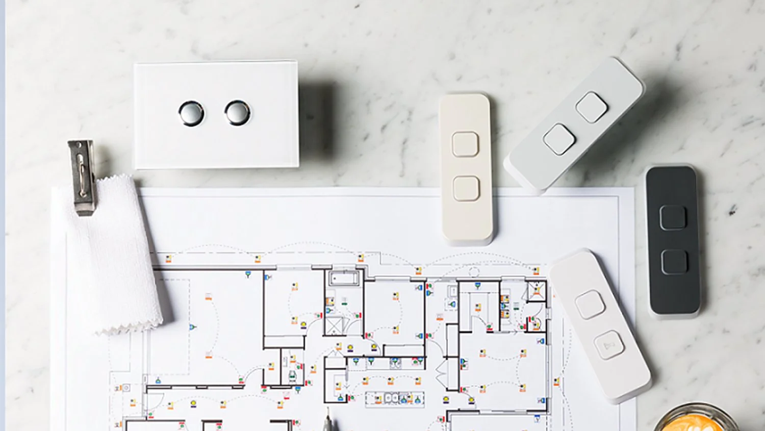 Electrical wiring plan on paper surrounded by smart switches and control panels.