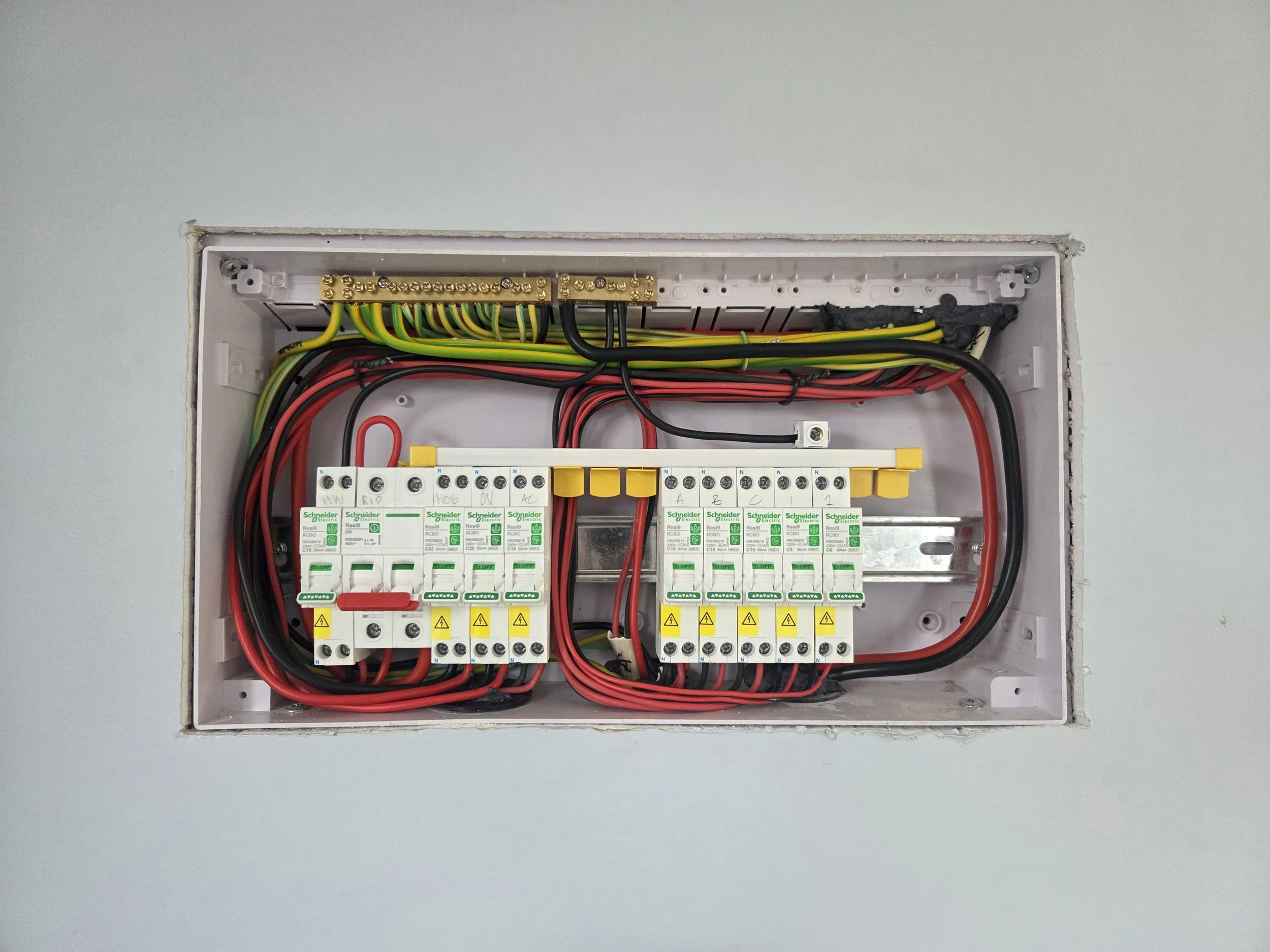 Open switch board with various coloured wires and circuit breakers.
