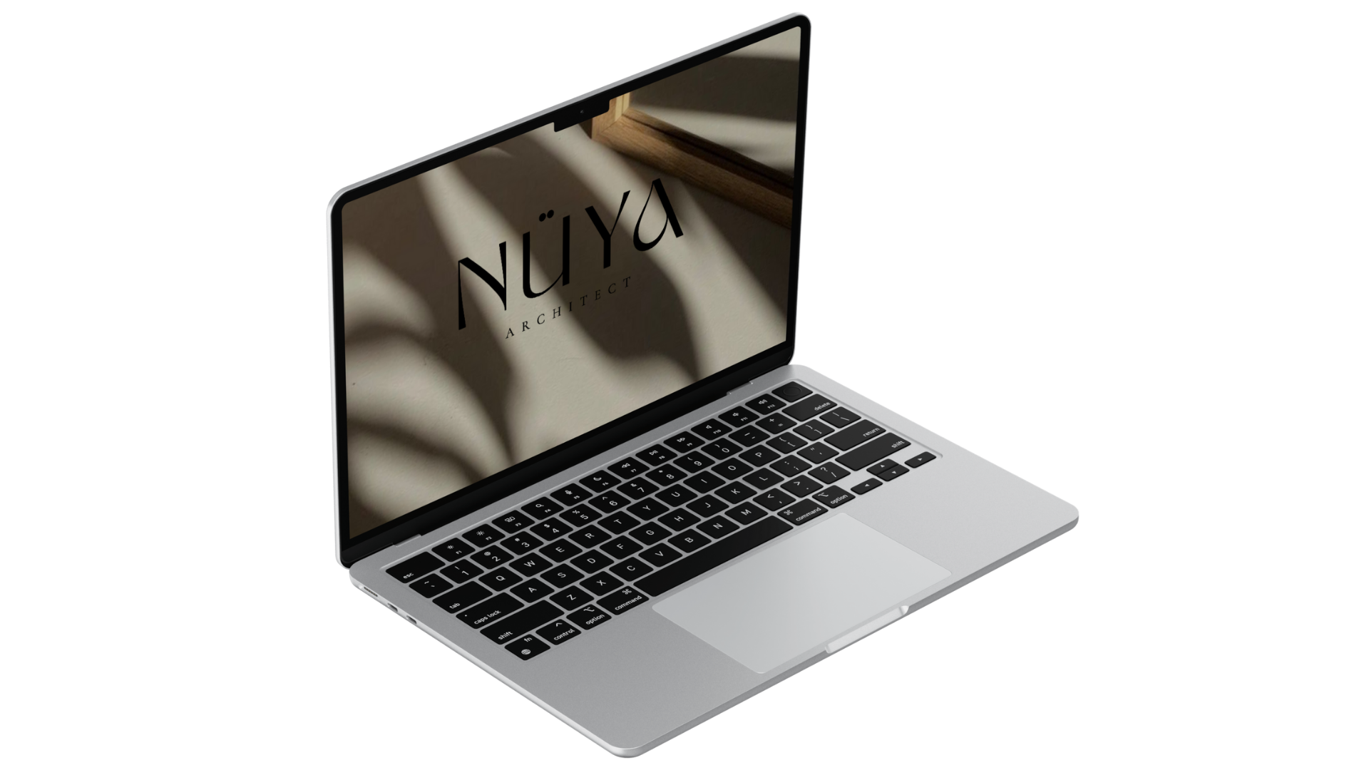 Un ordinateur portable gris avec un clavier noir, affichant à l'écran le texte 'Nüya Architect' sur un fond beige avec une ombre de feuille sur le mur.