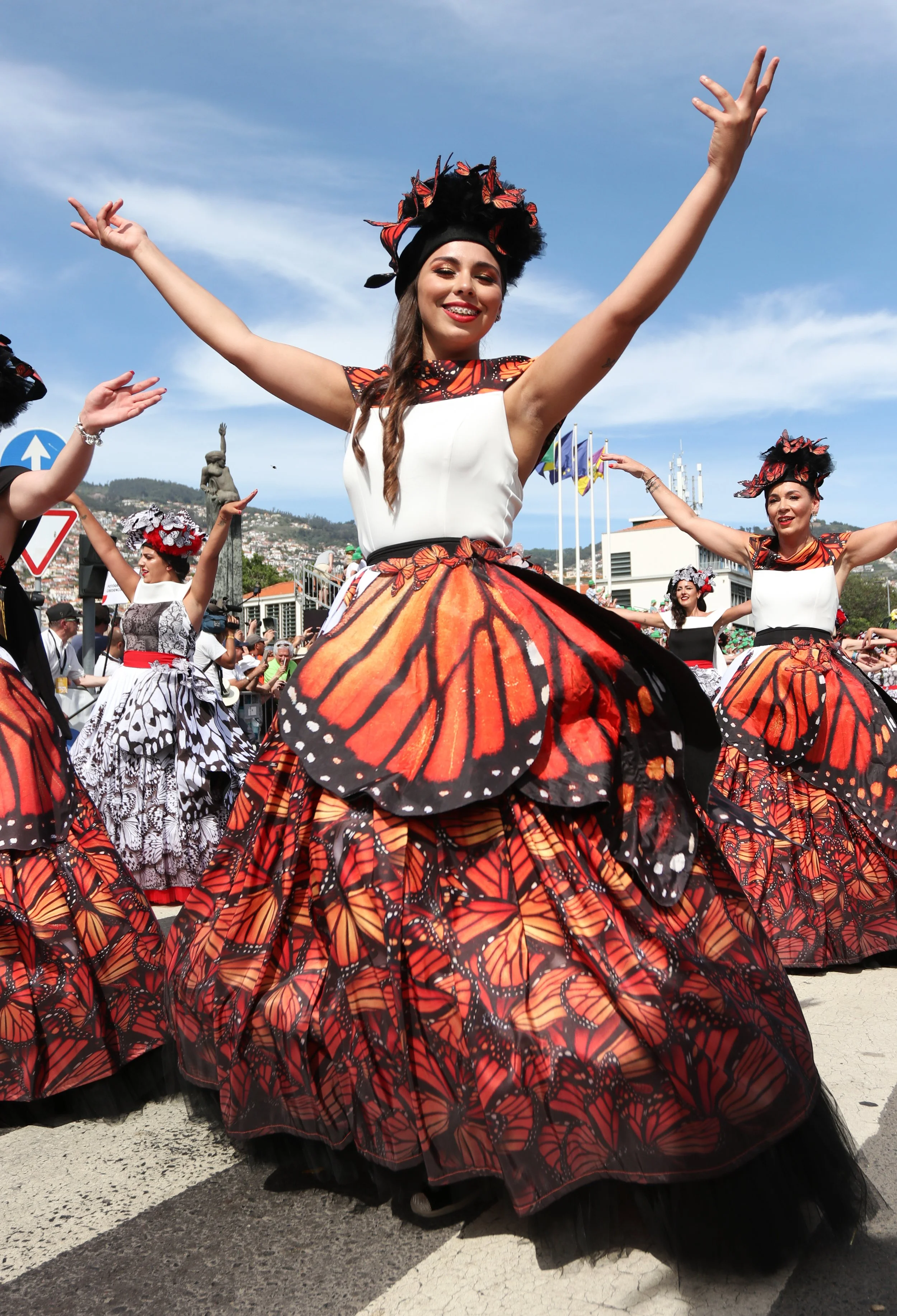Women in butterfly-inspired dresses dancing outdoors at a festival