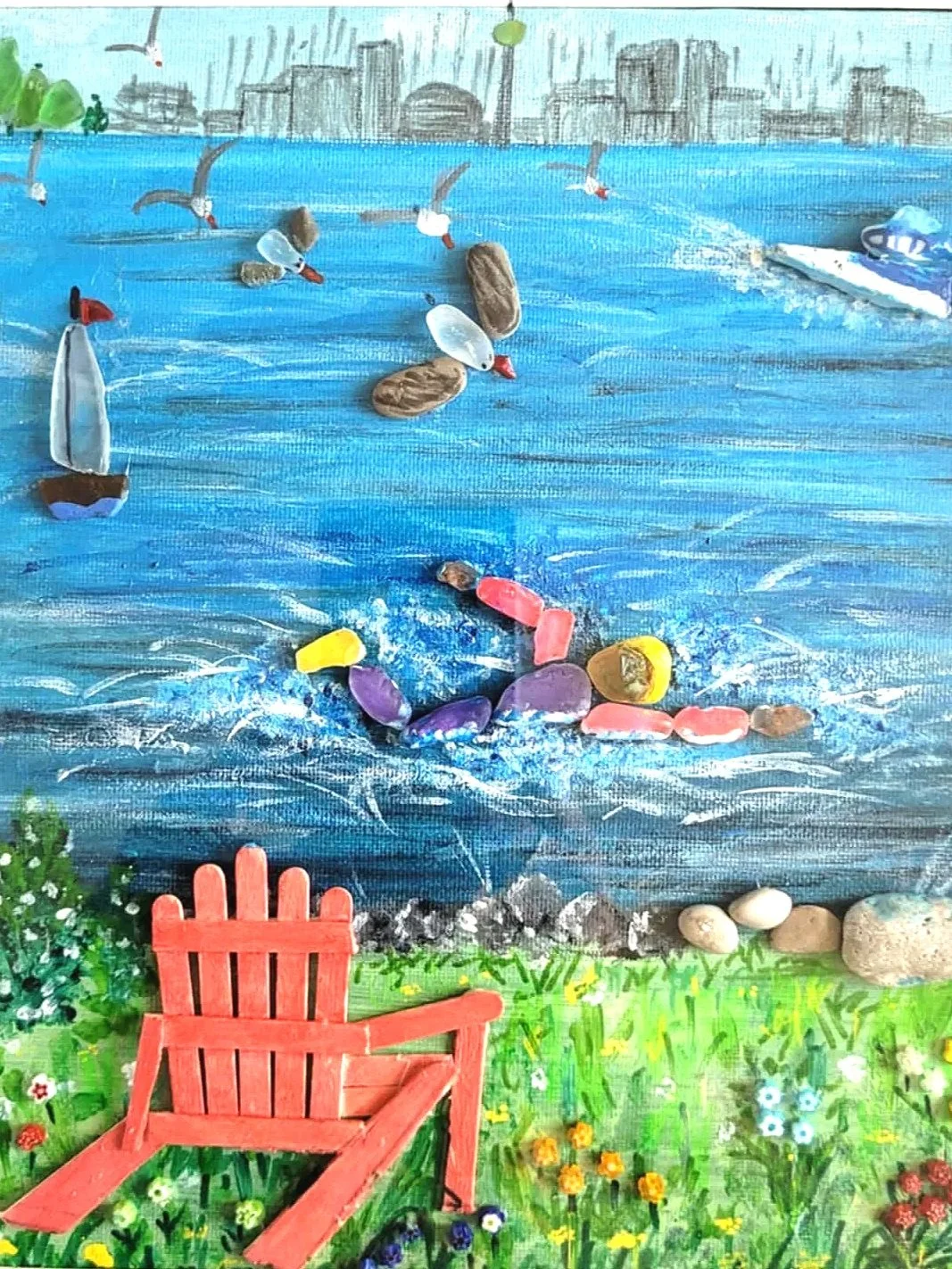 A colorful, mixed-media artwork of a lakeside scene featuring a blue lake with floating rocks, a small sailboat, seagulls flying over, and a green grassy area with a red Adirondack chair and flowers.