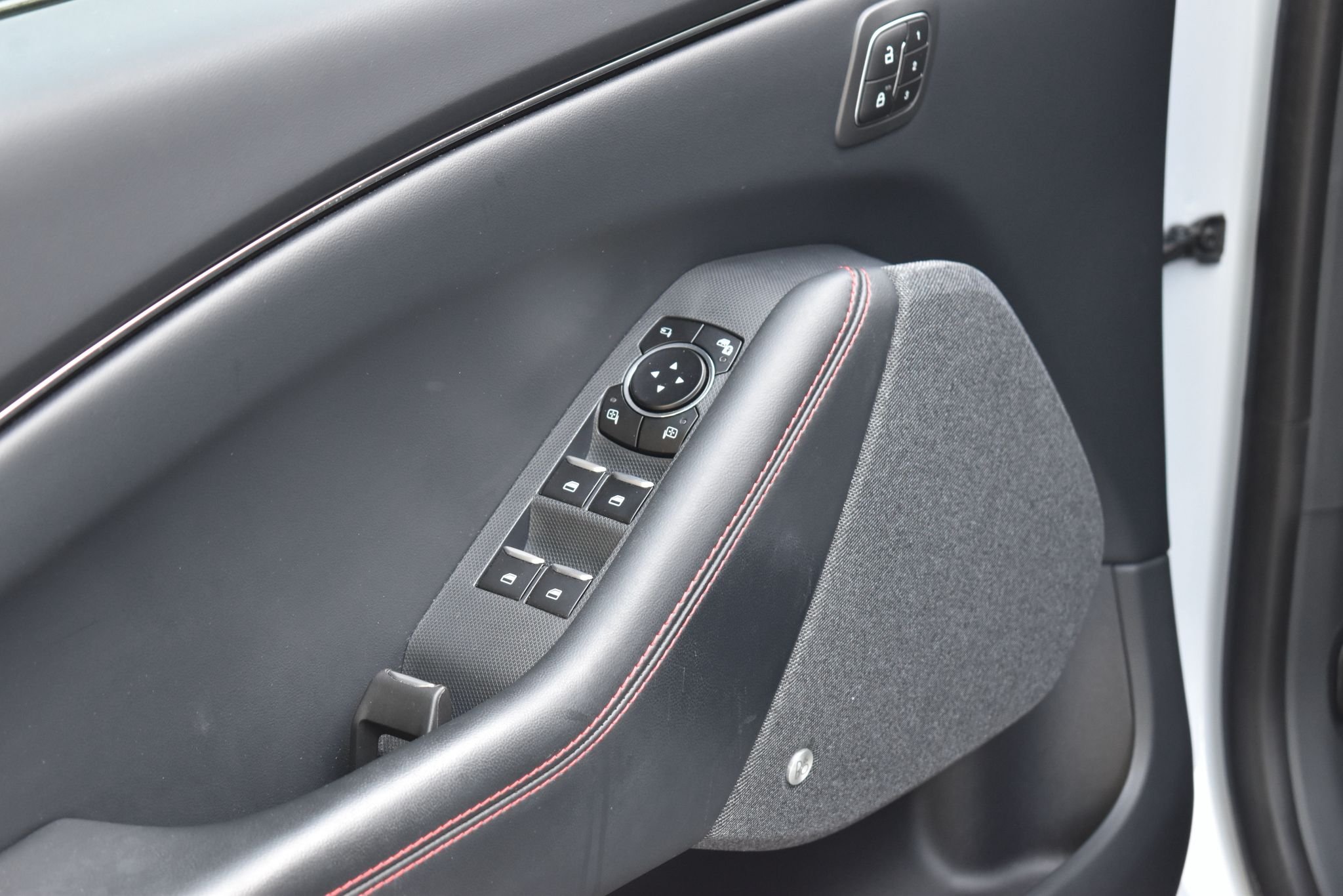 Consoles de controle do carro na porta do passageiro, com botões para travar e destravar as portas, além de botões para ajustar os espelhos retrovisores.
