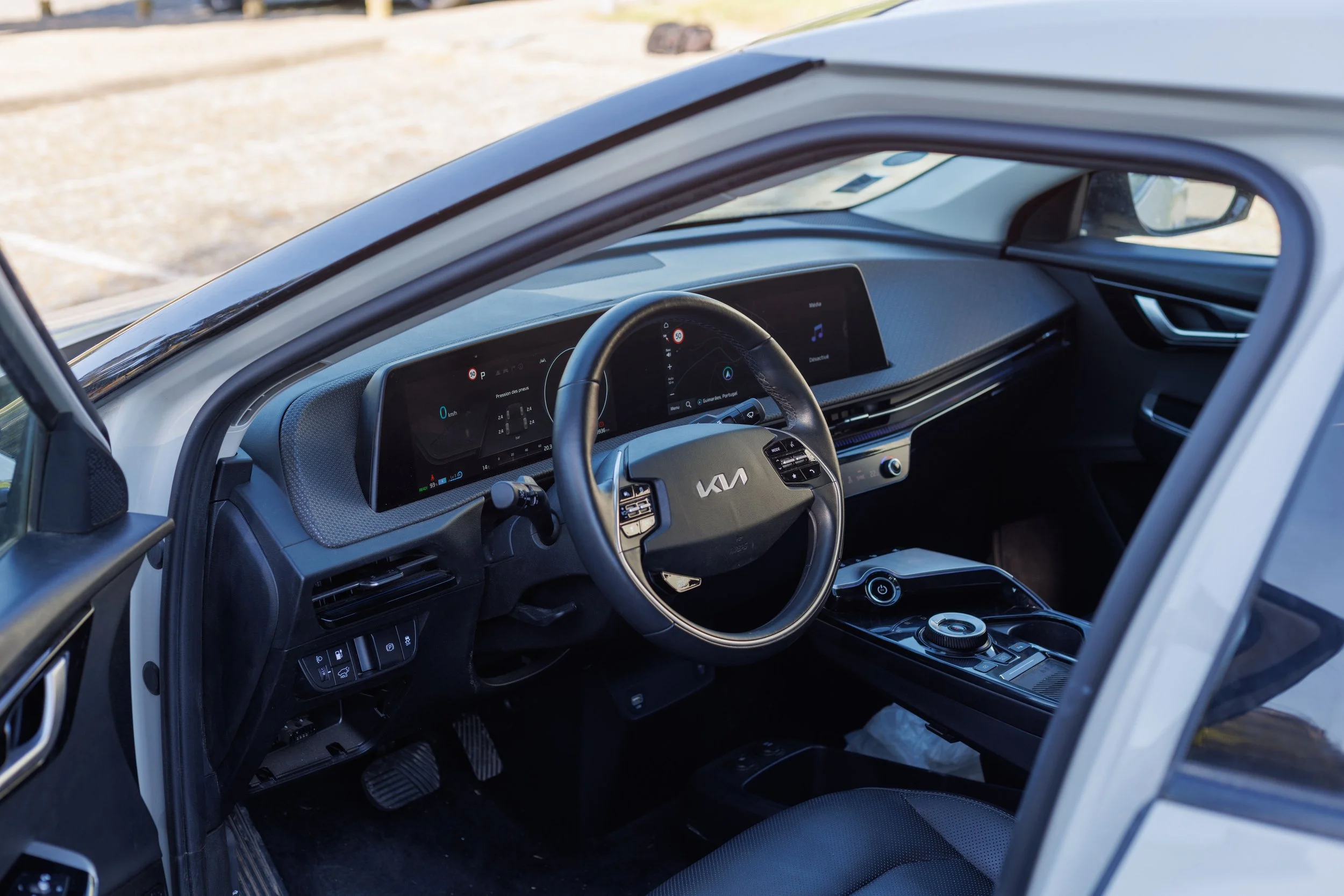 Interior de um carro elétrico, mostrando o painel digital e o volante com o logo da Kia.