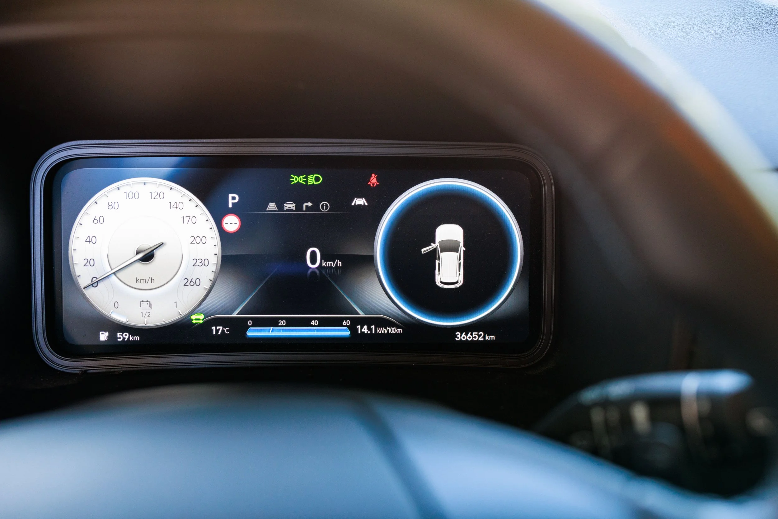 Painel de instrumentos de carro digital mostrando velocidade de 0 km/h, nível de combustível, temperatura de 17°C, autonomia de 59 km, consumo de 14.1 kWh/100km e quilometragem de 36.652 km, com indicadores de luz ativada.
