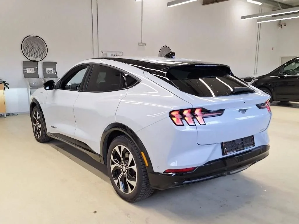 Carro elétrico branco estacionado em um ambiente interno, visto de trás.