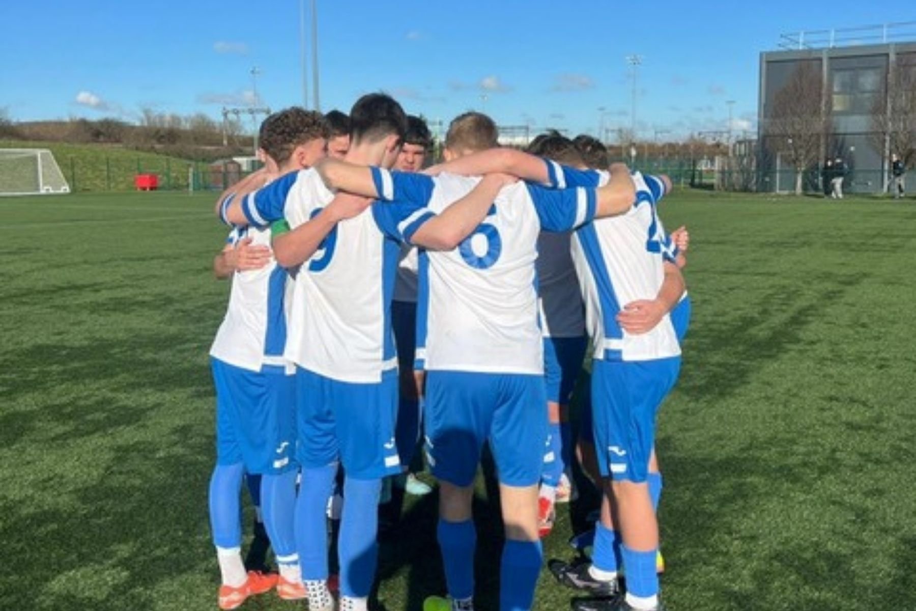 P16 football team in a team huddle before a match