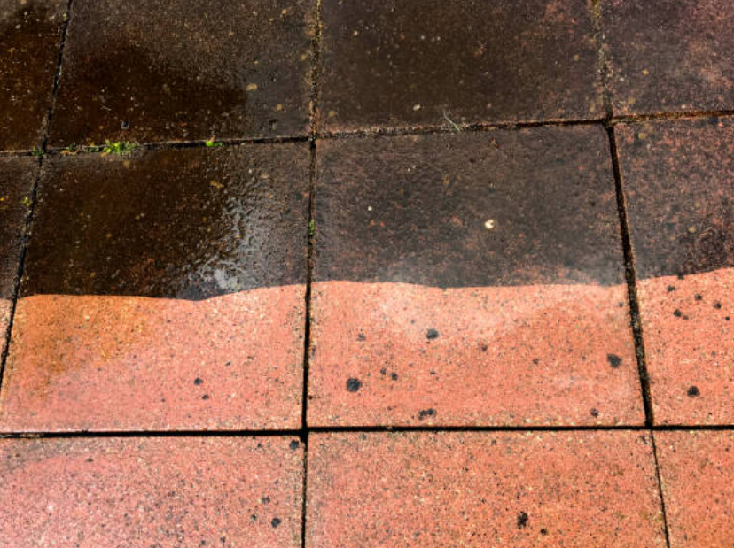 Trottoir en pavés humides, moitié foncés et moitié clairs, avec une ligne séparatrice entre les deux couleurs.