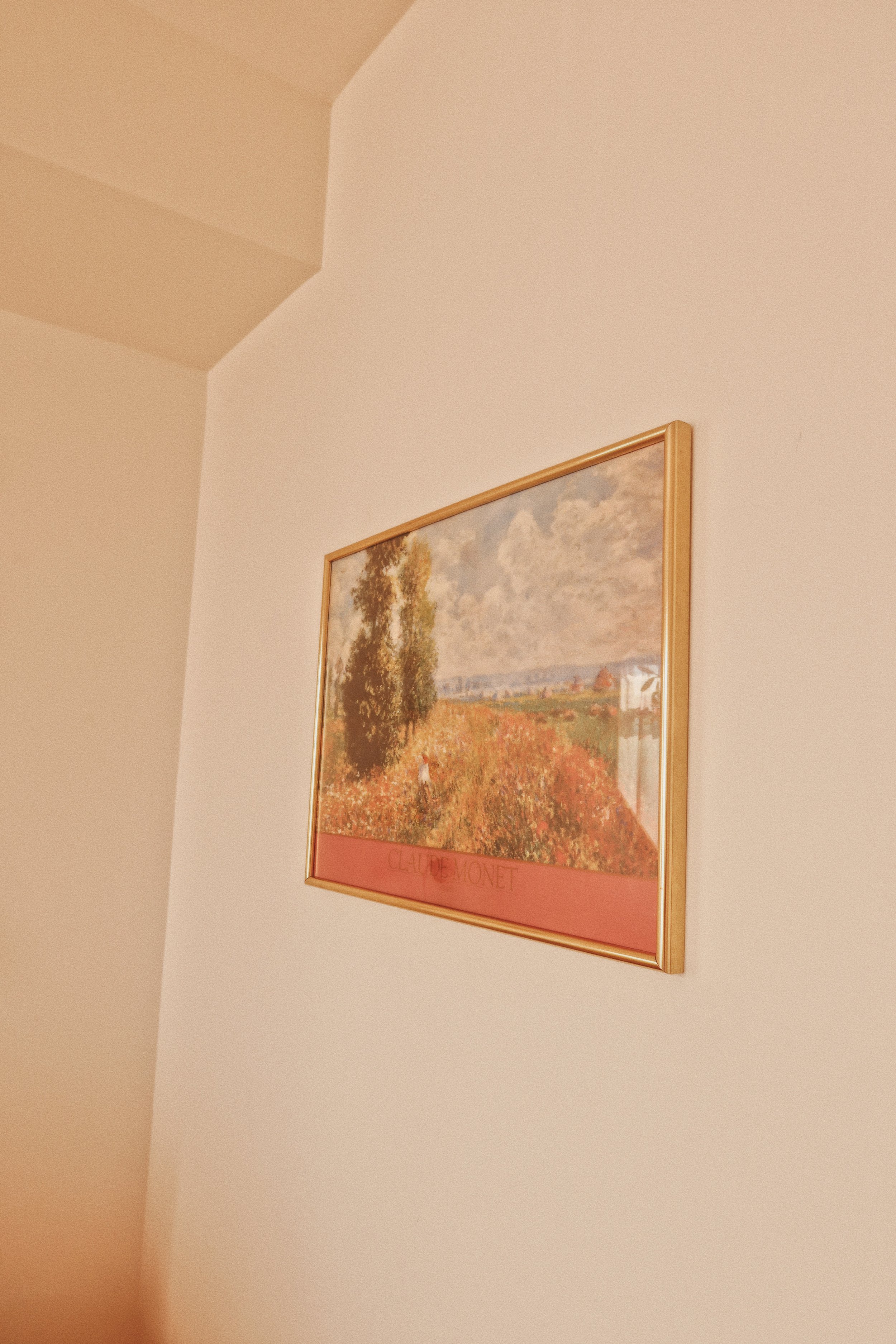 Framed Claude Monet painting hanging on a beige wall.