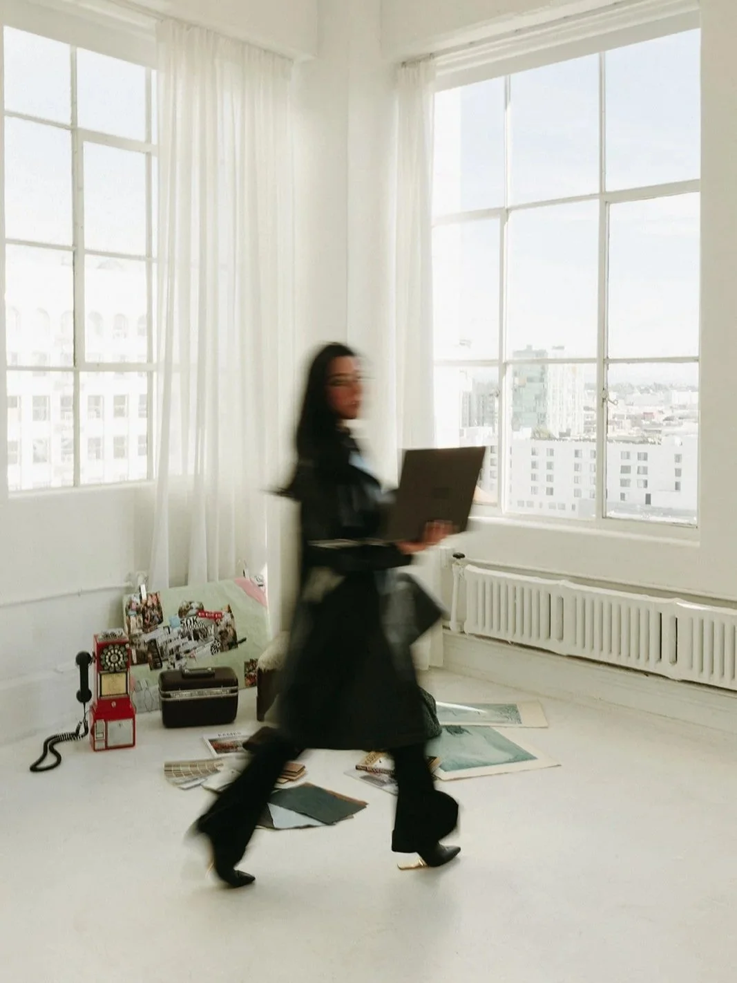 Kate Kramer, Los Angeles interior decorator and founder of Curated by Kramer, walking through a bright design studio with a laptop and material samples
