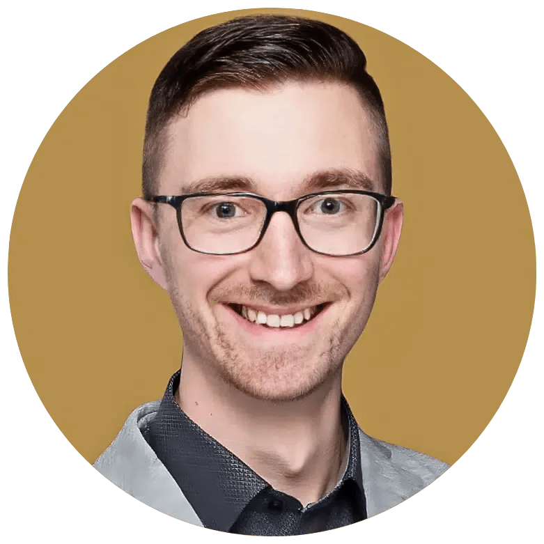 Ein lächelnder junger Mann mit Brille, braunem Haar und dunklem Hemd vor einem goldenen Hintergrund.