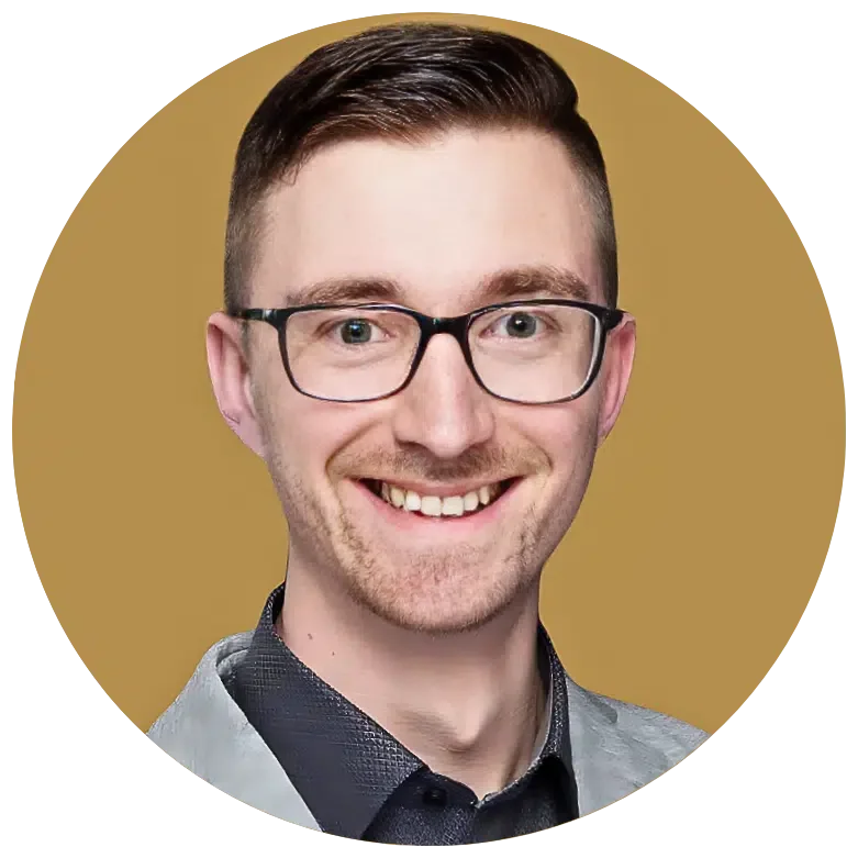 Ein lächelnder junger Mann mit Brille, braunem Haar und dunklem Hemd vor einem goldenen Hintergrund.