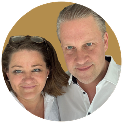 Ein Mann und eine Frau machen ein Selfie vor einem beigen Hintergrund. Beide lachen leicht und schauen in die Kamera.