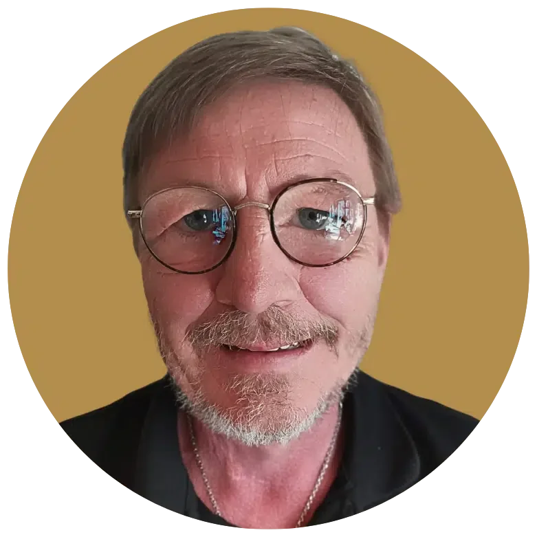 Nahaufnahme eines lächelnden Mannes mit Brille vor gelbem Hintergrund.