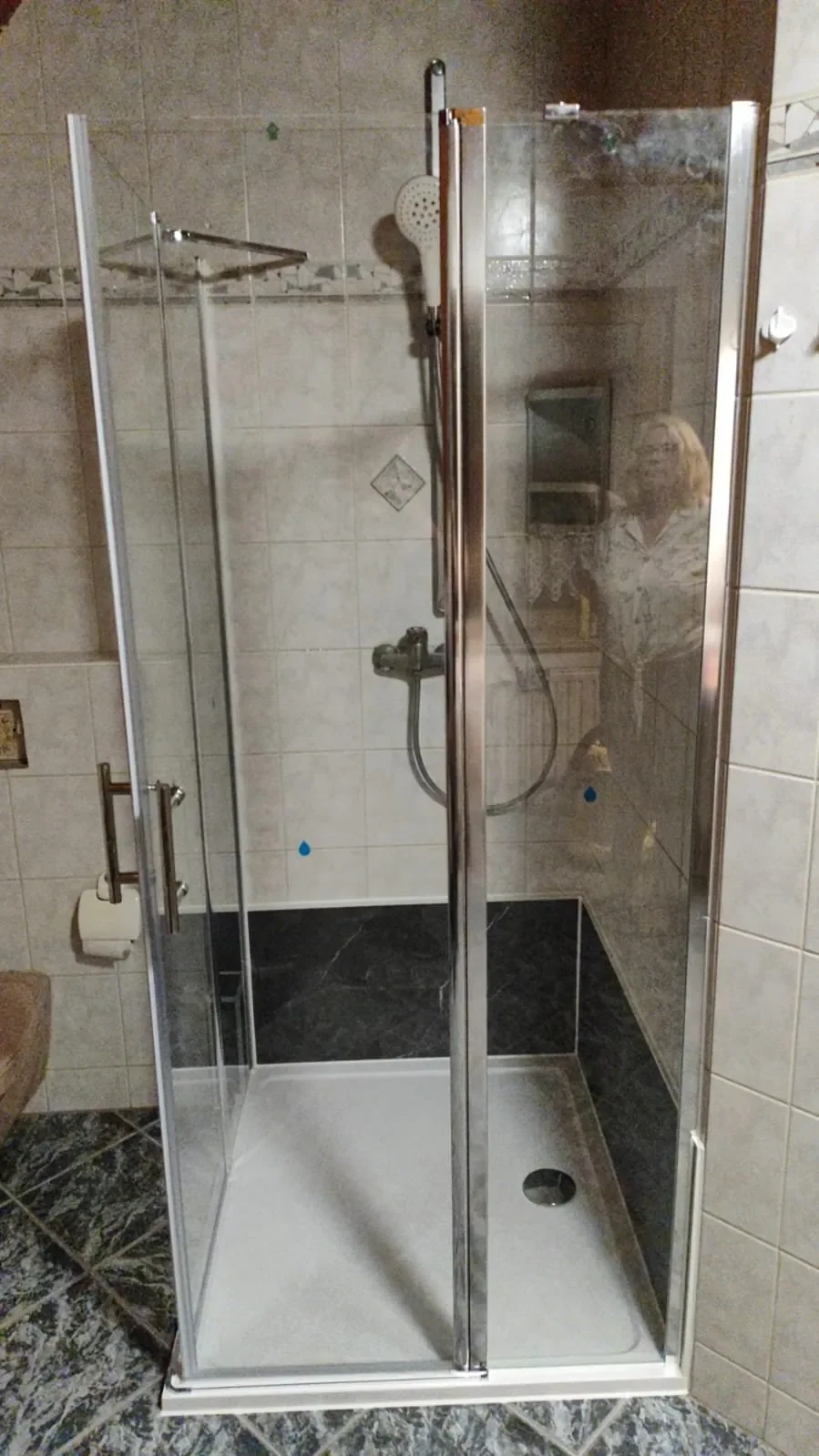 Kleines Duschkabinen mit Glaswänden und Duschkopf in einem Badezimmer.