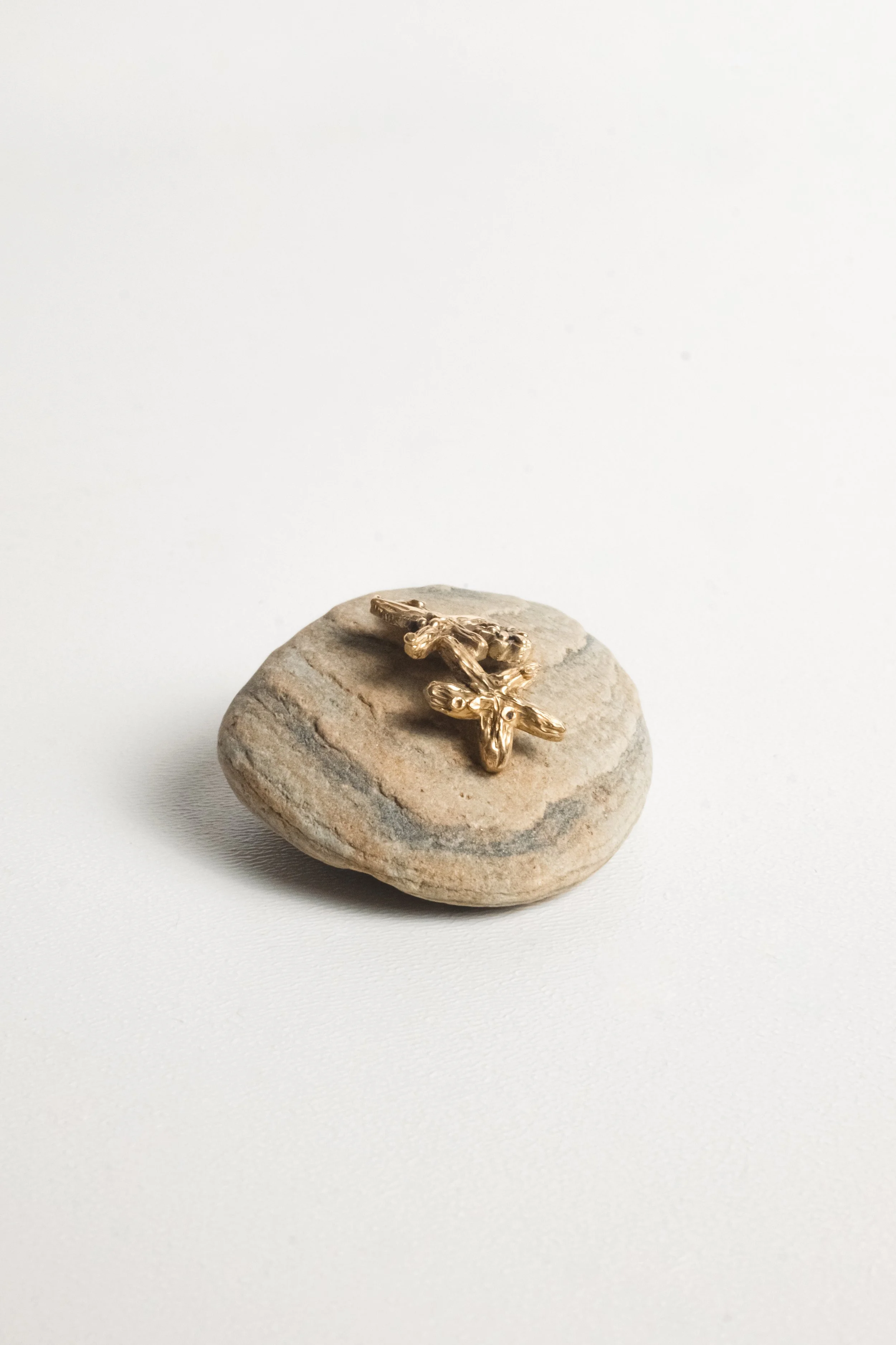 Gold earrings on a smooth, round stone against a plain white background