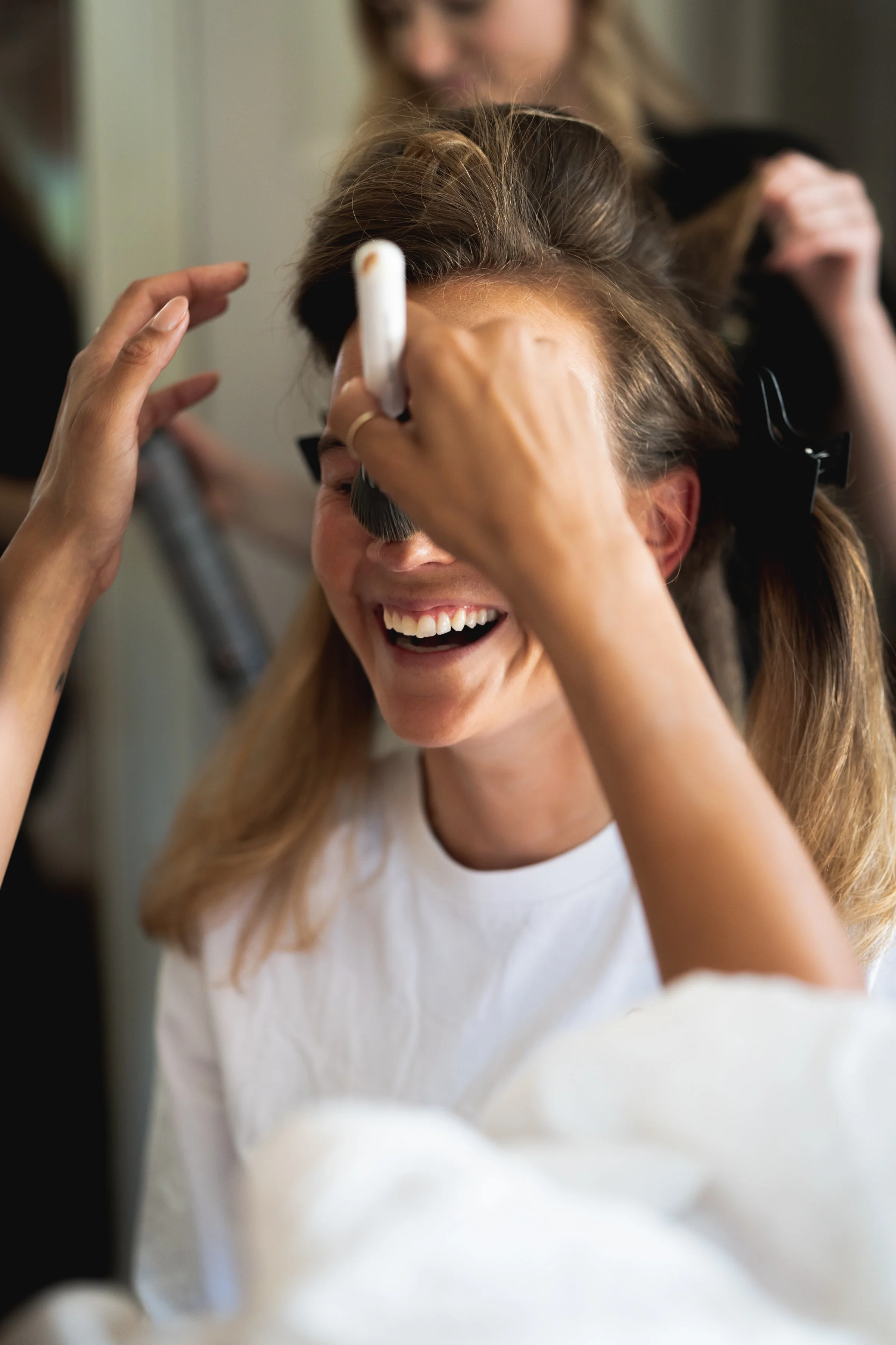 Vrouw die lacht terwijl haar haar wordt gekamd door een kapper.