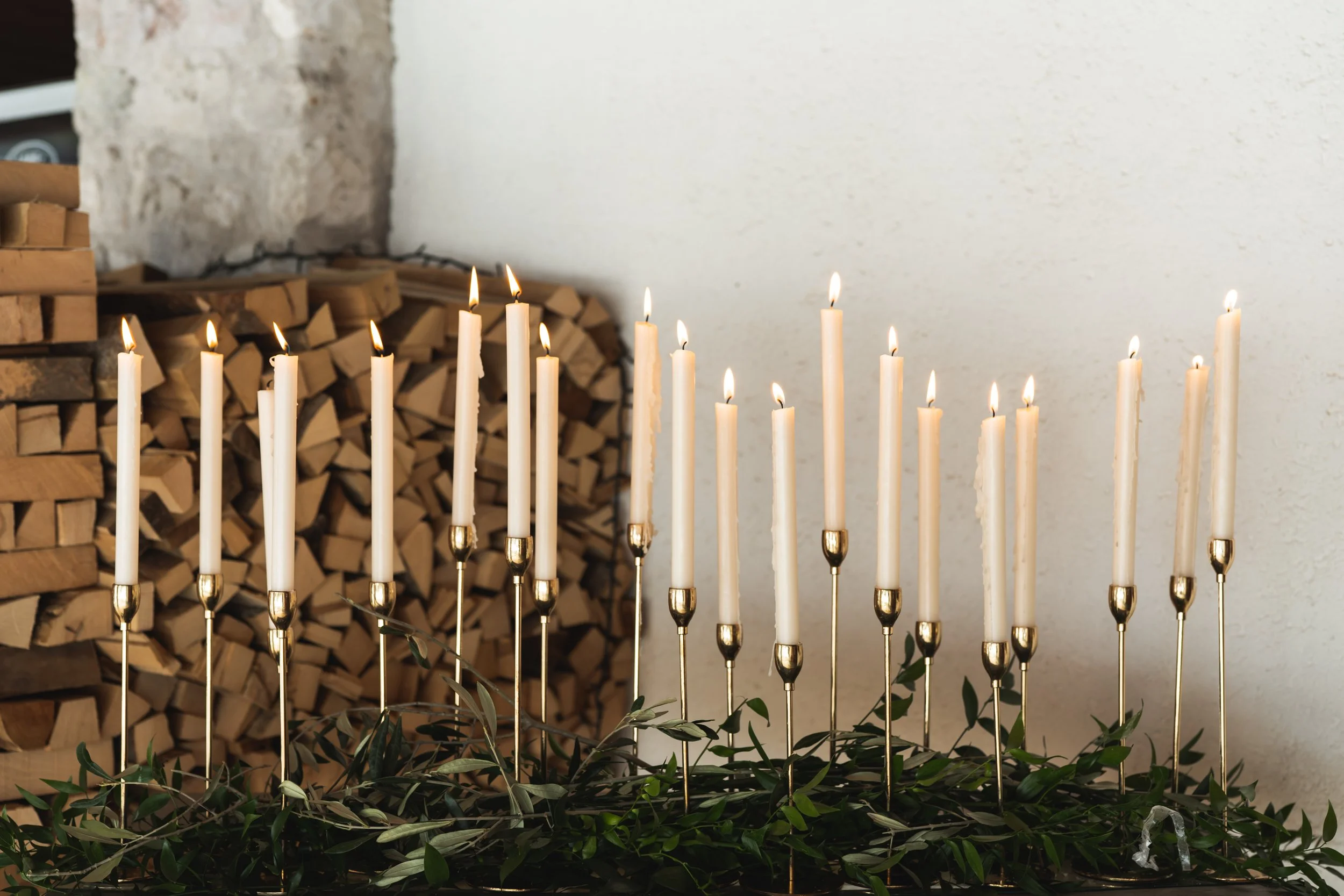Kaarsen op een feestelijke decoratie, met houtgestapelde brandhout op de achtergrond.