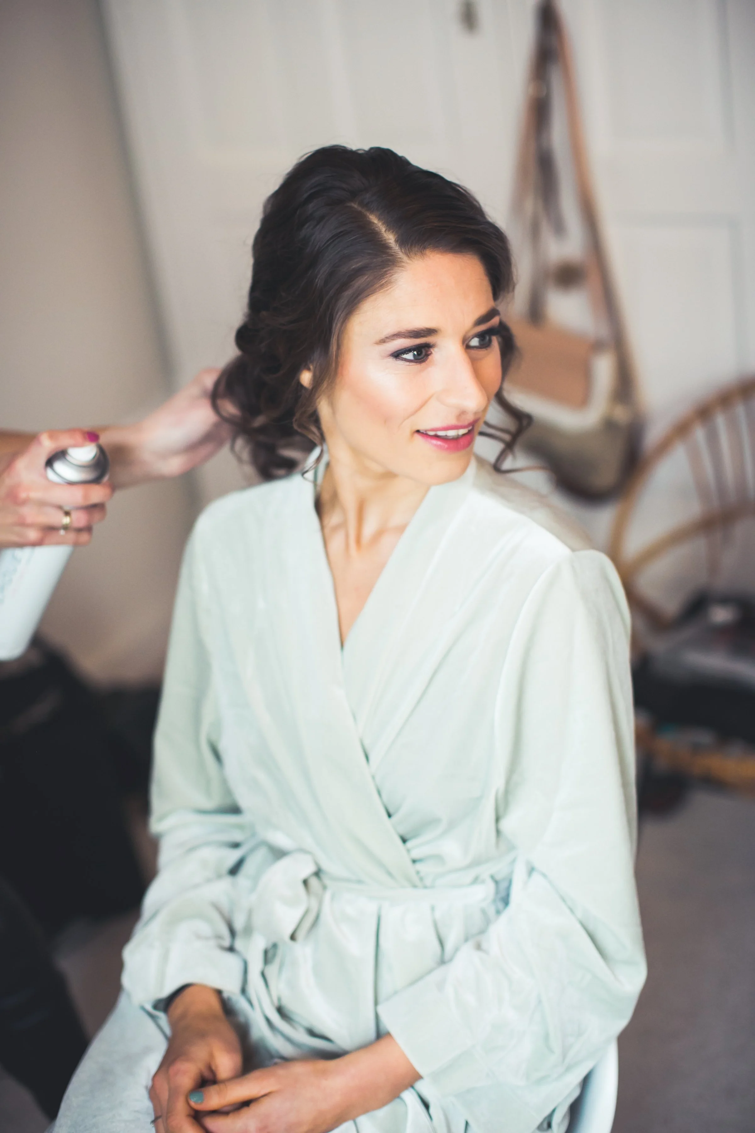 Vrouw krijgt haar haar gedaan door een stylist in een kamer met witte muren.