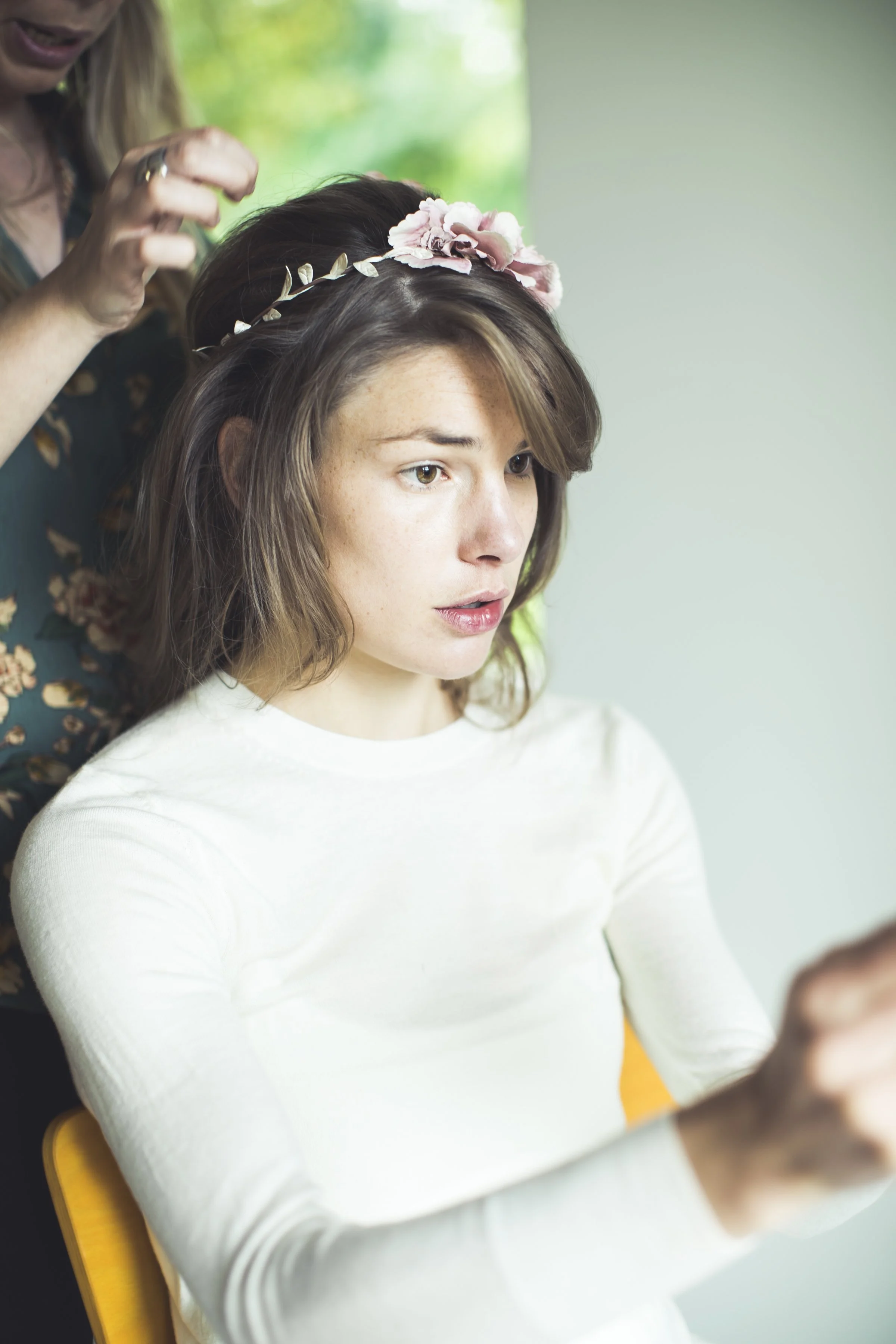 Vrouw krijgt een bloemenhoofdband geplaatst door een stylist.