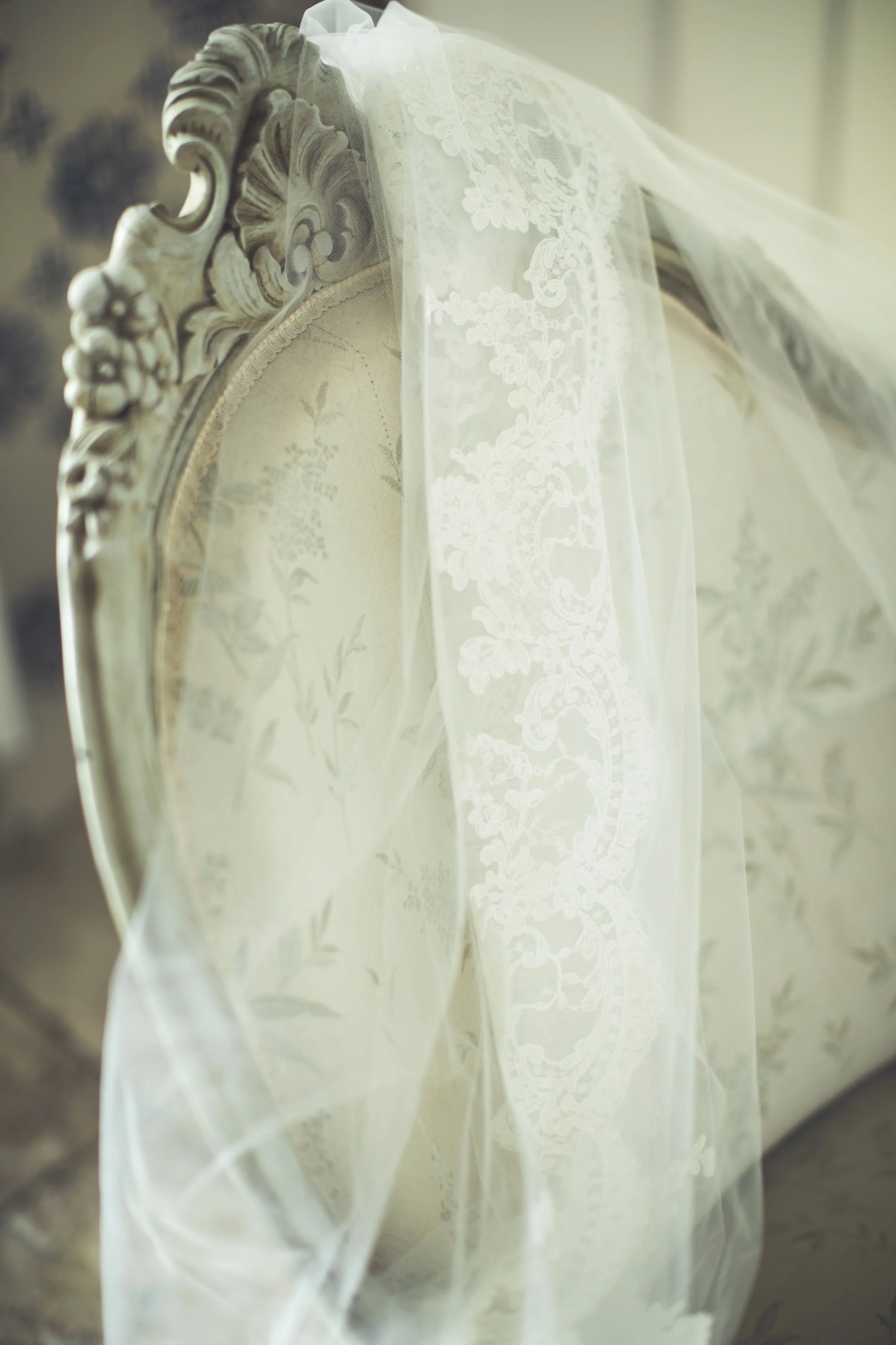 Een antiek, versierd hoofdeinde met een lichte, doorzichtige voile met lace details eroverheen.