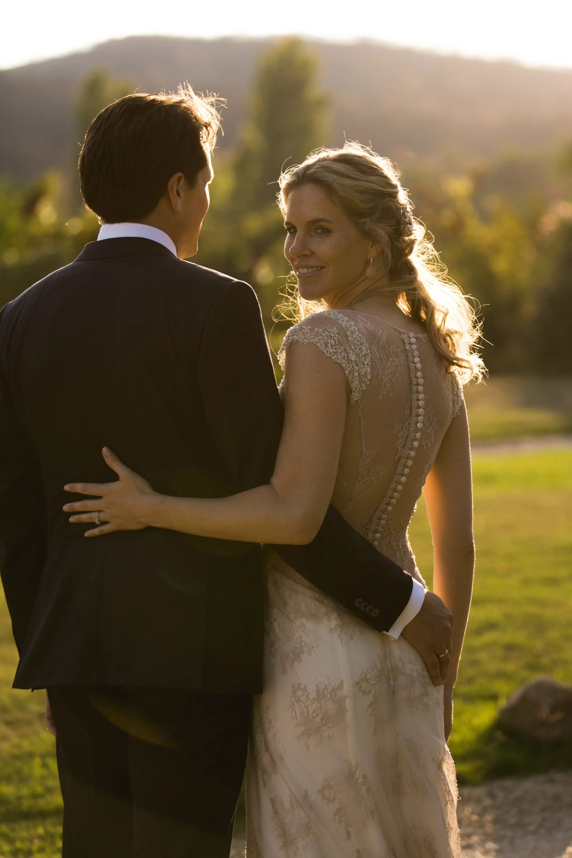 Een getrouwd paar op hun huwelijksdag, omringd door een natuurlijke buitenomgeving tijdens zonsondergang.