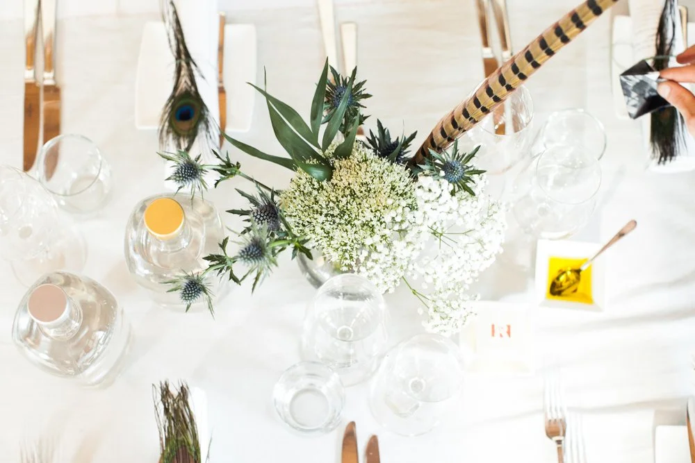 Een tafel met een bloemstuk en glazen, klaar voor een etentje.