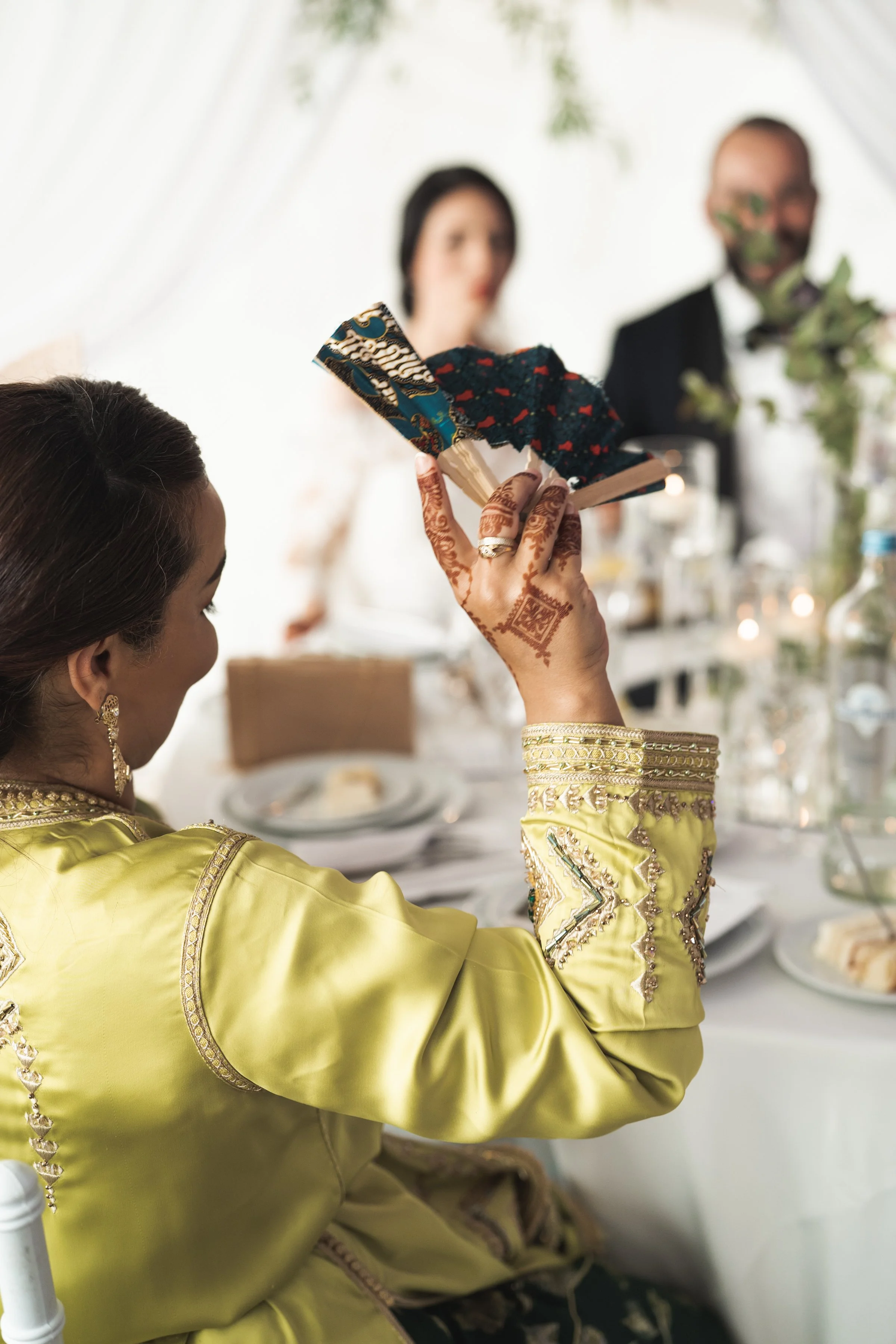 Een vrouw in een geel geklede jurk die met een handketting wordt gehalsd, terwijl mensen op de achtergrond toekijken.