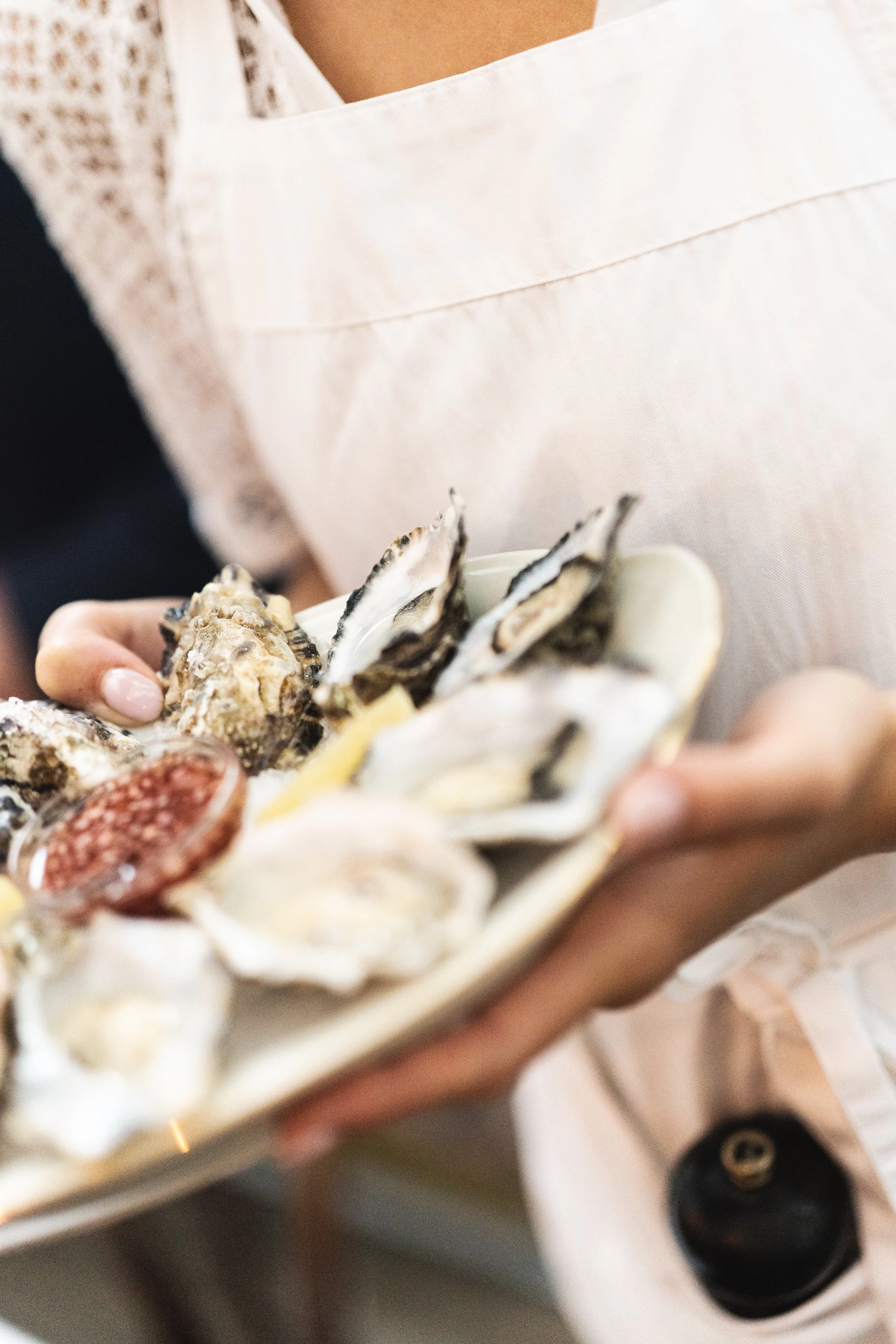 Personeel serveert een romige schaal met verschillende verse zeevruchten zoals oesters, mosselen en schelpen