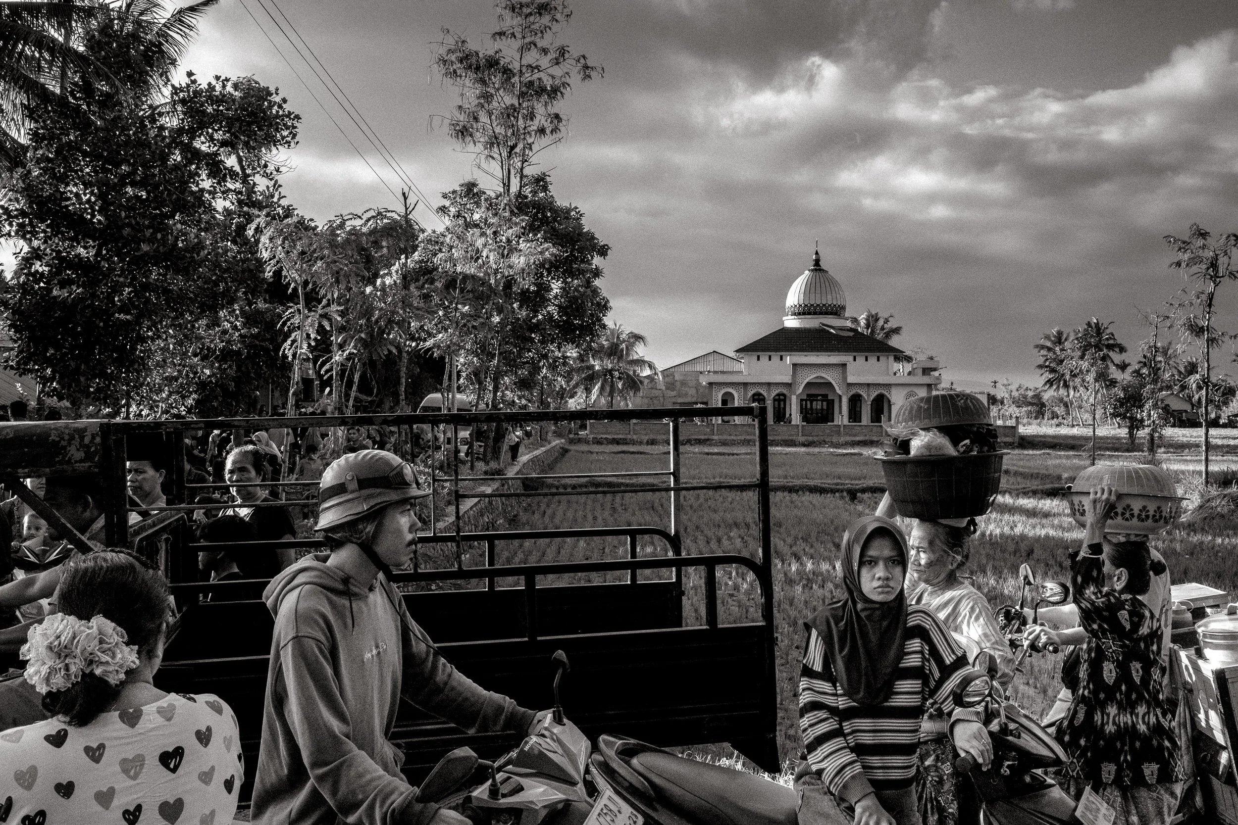 Vehicles and pedestrians share the road as the wedding party moves into a procession. Central Lombok, Indonesia. 6 August 2025.