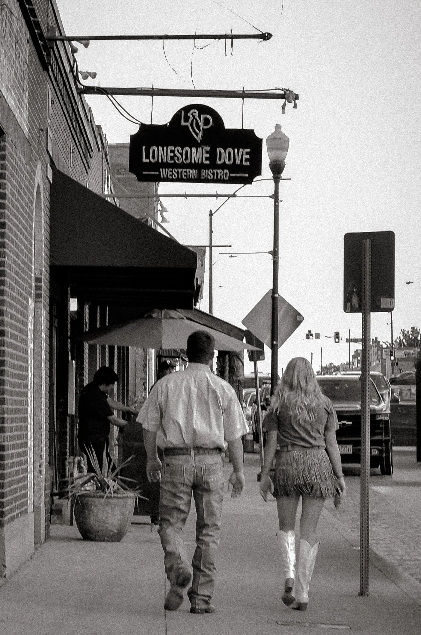 Two people walk in cowboy attire along the pavement. Fort Worth, Texas, USA. 10 August 2023.