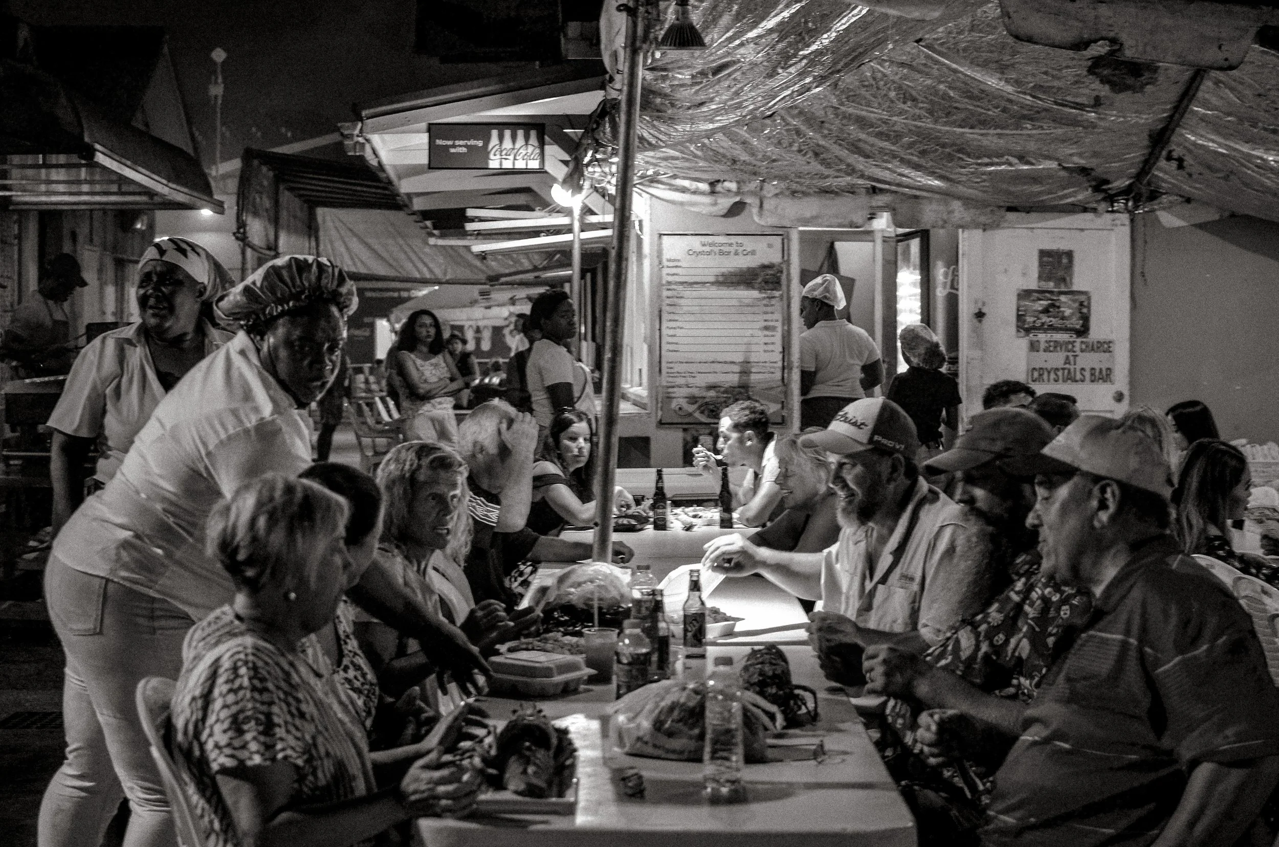 Communal tables fill quickly as the Fish Fry begins for the evening. Oistins, Barbados. December 2022.