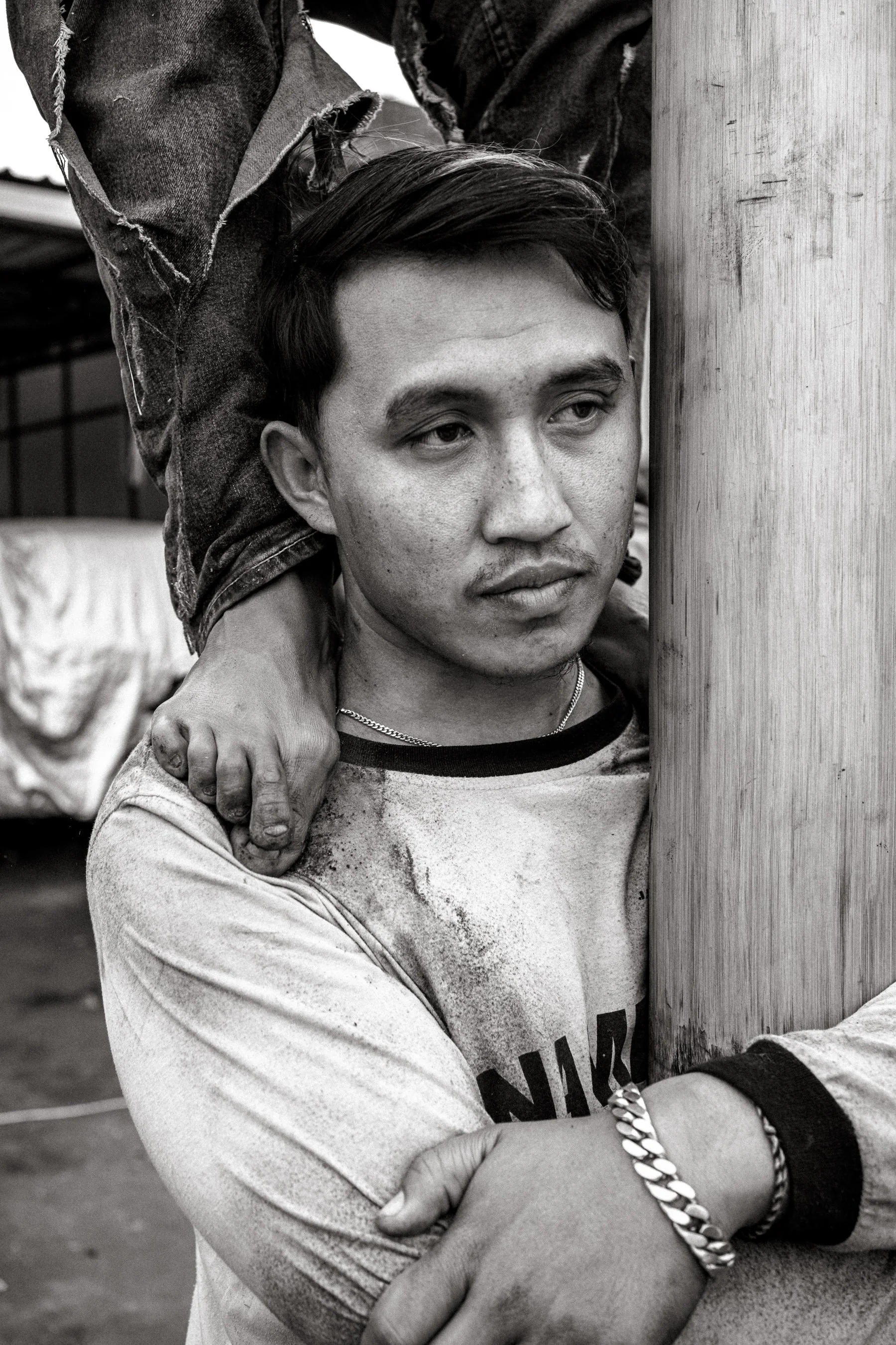A competitor grips the pole mid-climb. This man remained at the base throughout, supporting others as they mounted and stood on his back, toes curled for grip. Ngadas, East Java, Indonesia. 21 August 2025.