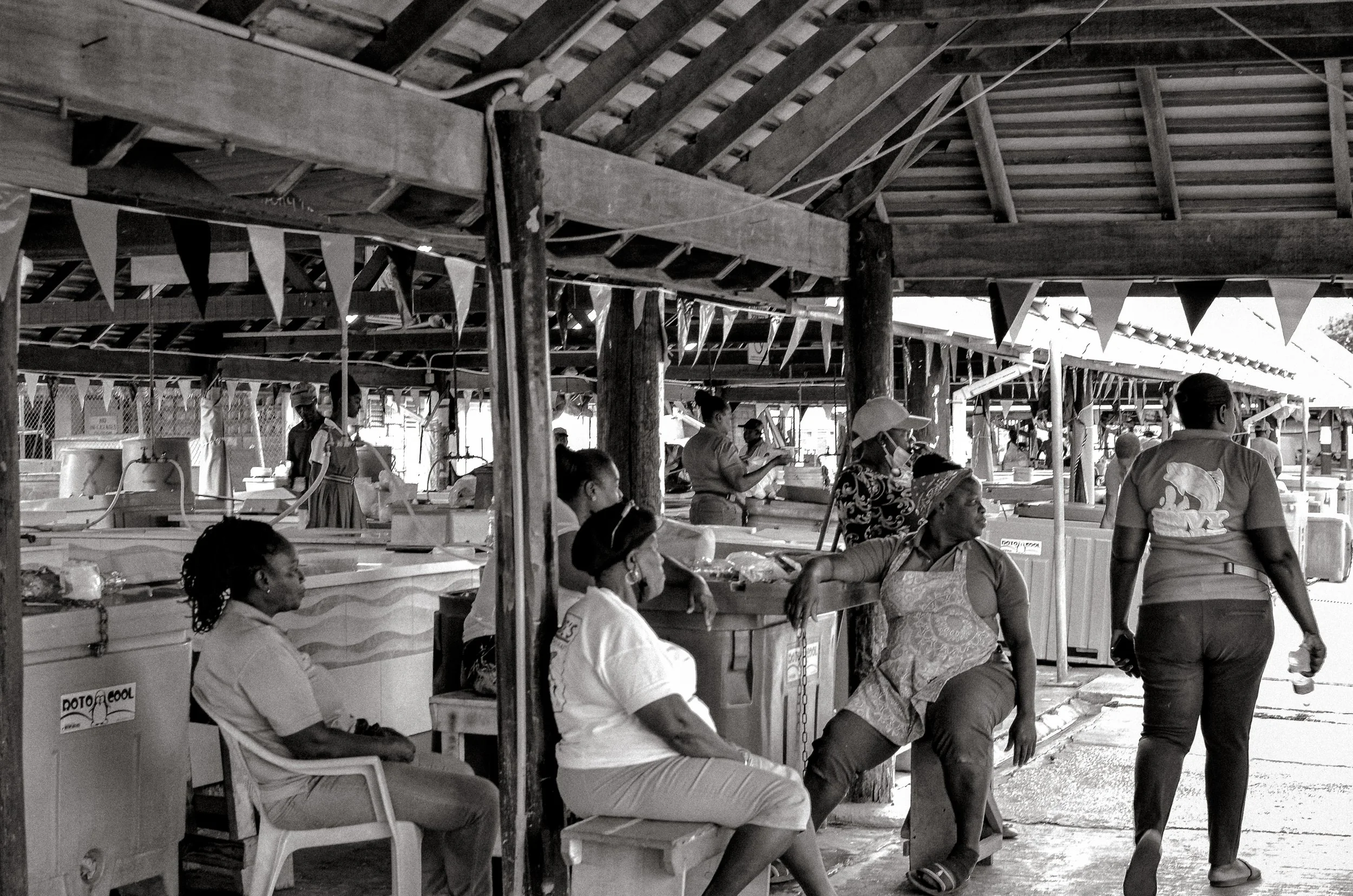 After closing, workers sit together beneath the open roof. Oistins, Barbados. December 2022.