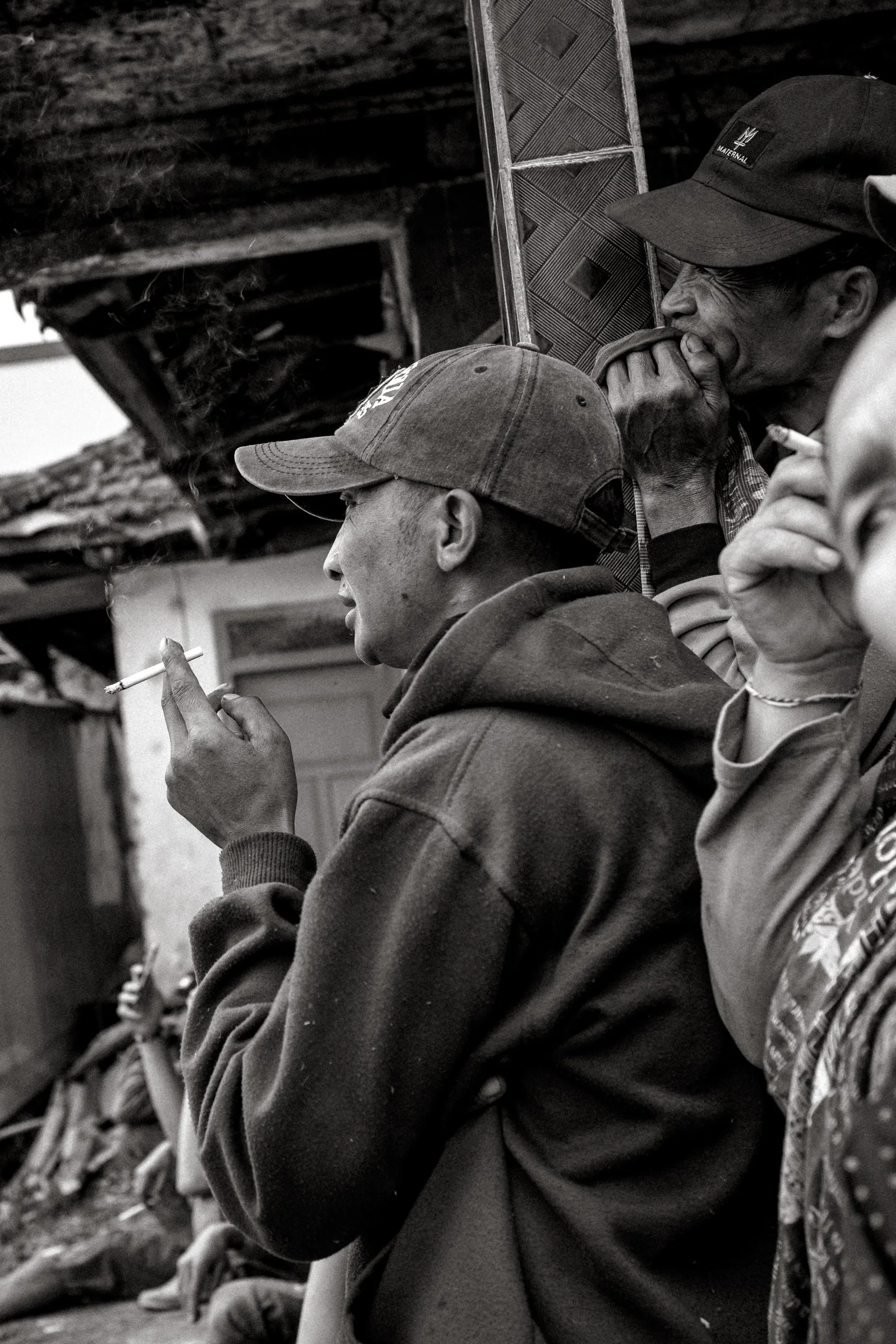 Spectators watch closely from the side, cigarettes in hand. Ngadas, East Java, Indonesia. 21 August 2025.