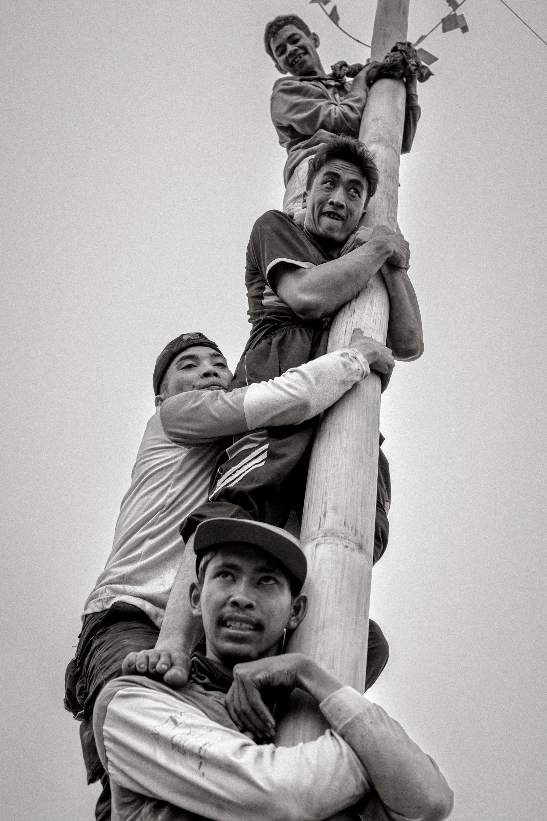 Competitors form a human ladder on the greased pole to lift a teammate higher