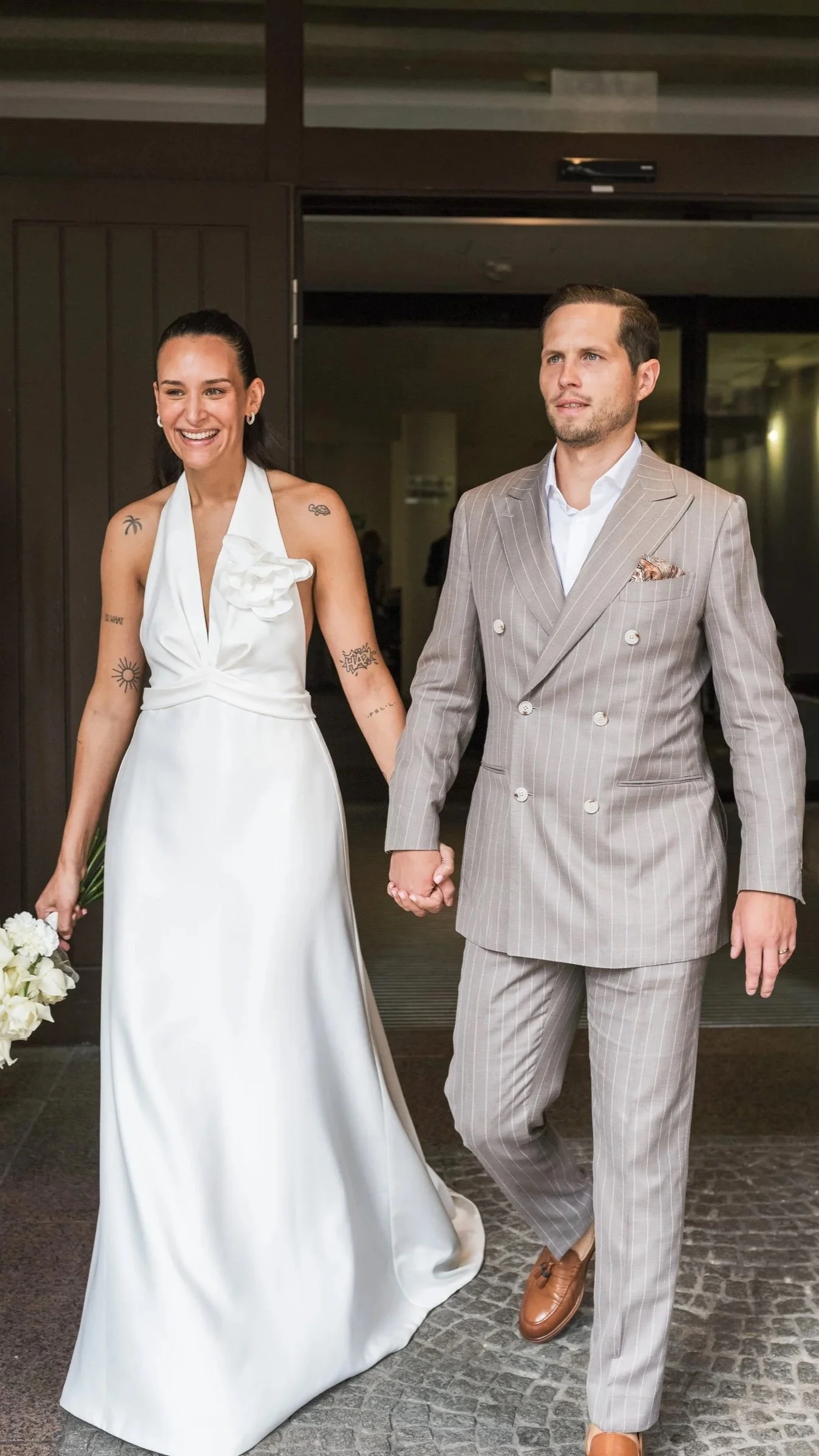 Bride and groom walking out of wedding venue holding hands