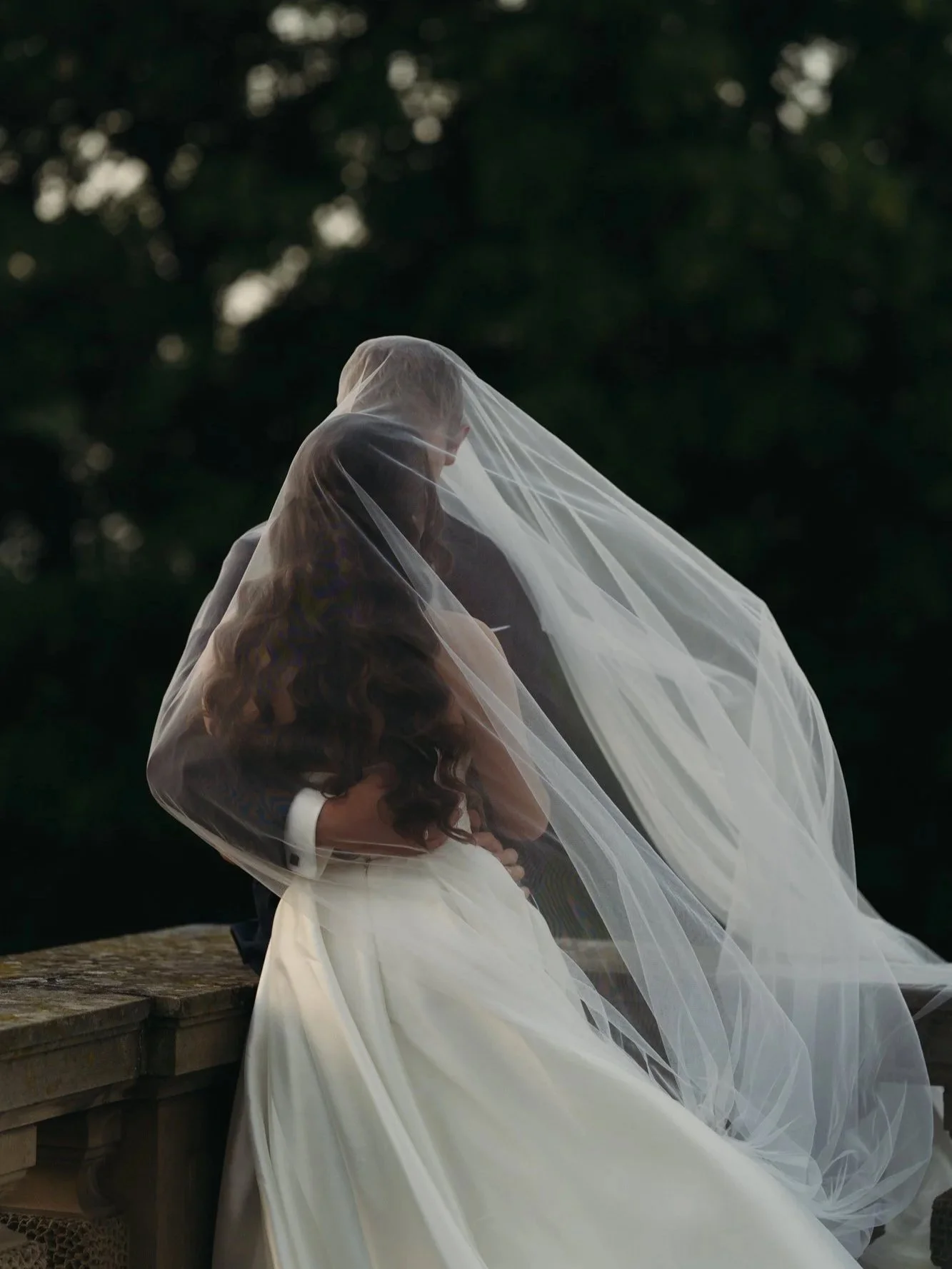 Bride and groom portrait under wedding veil in natural light