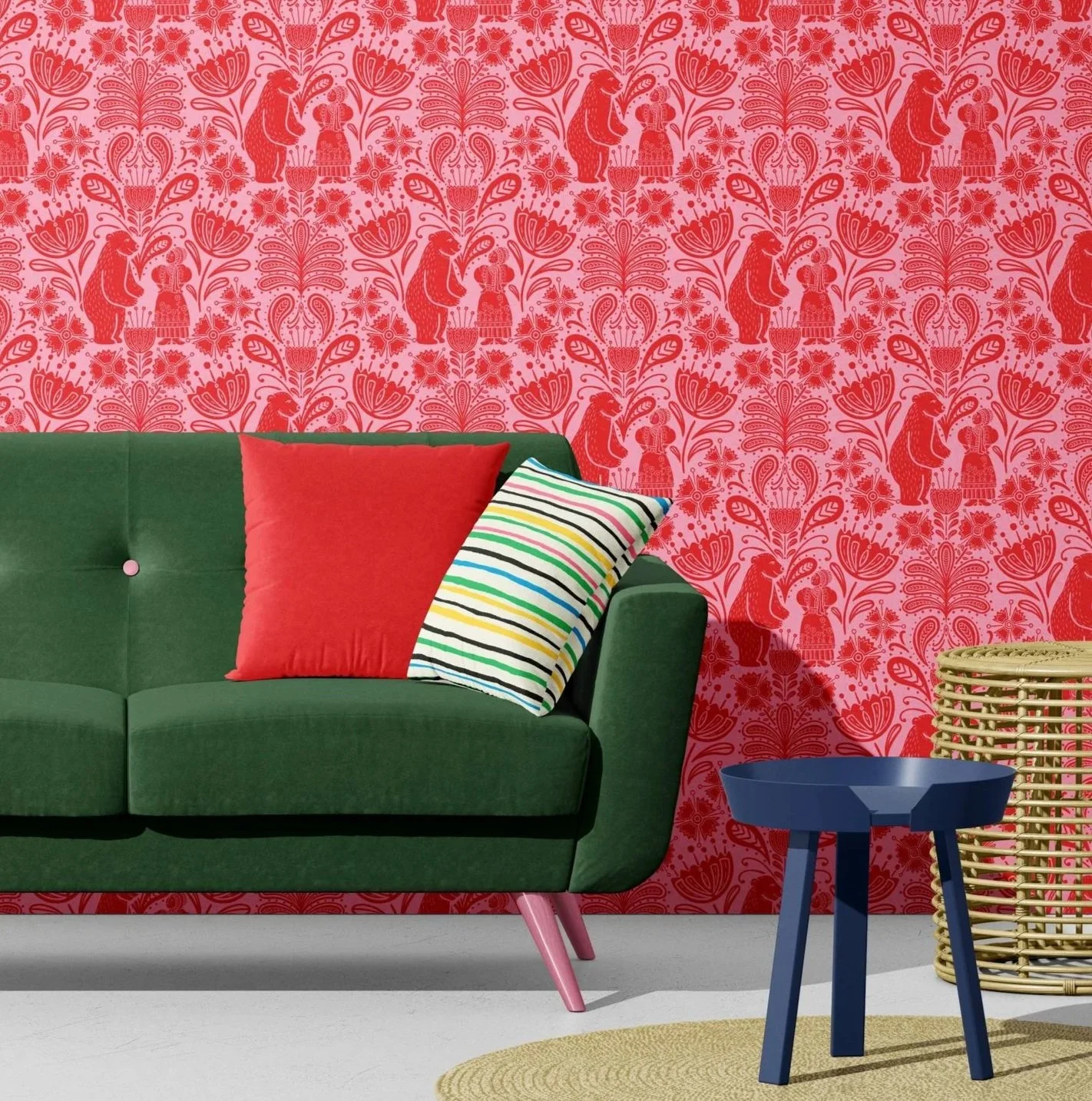 Living room with a green sofa, pink floral and bear patterned wallpaper, two throw pillows (one solid pink and one striped multicolored), a blue side table, a wicker basket, and a beige round rug.