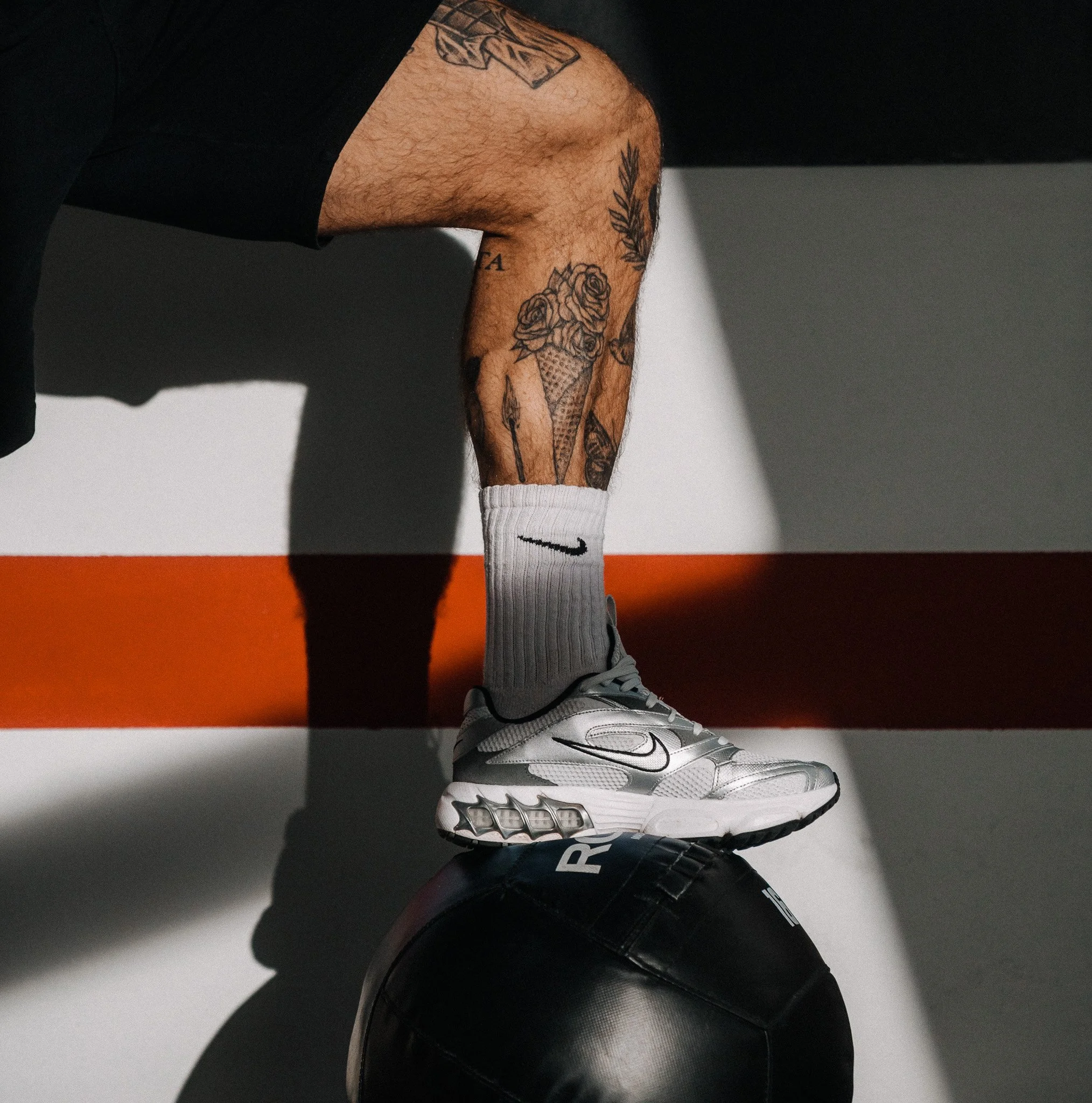 Athletisches Bein steht mit Trainingsschuh auf einem schwarzen Medizinball im Studio – funktionelles Krafttraining bei FORM-ID.