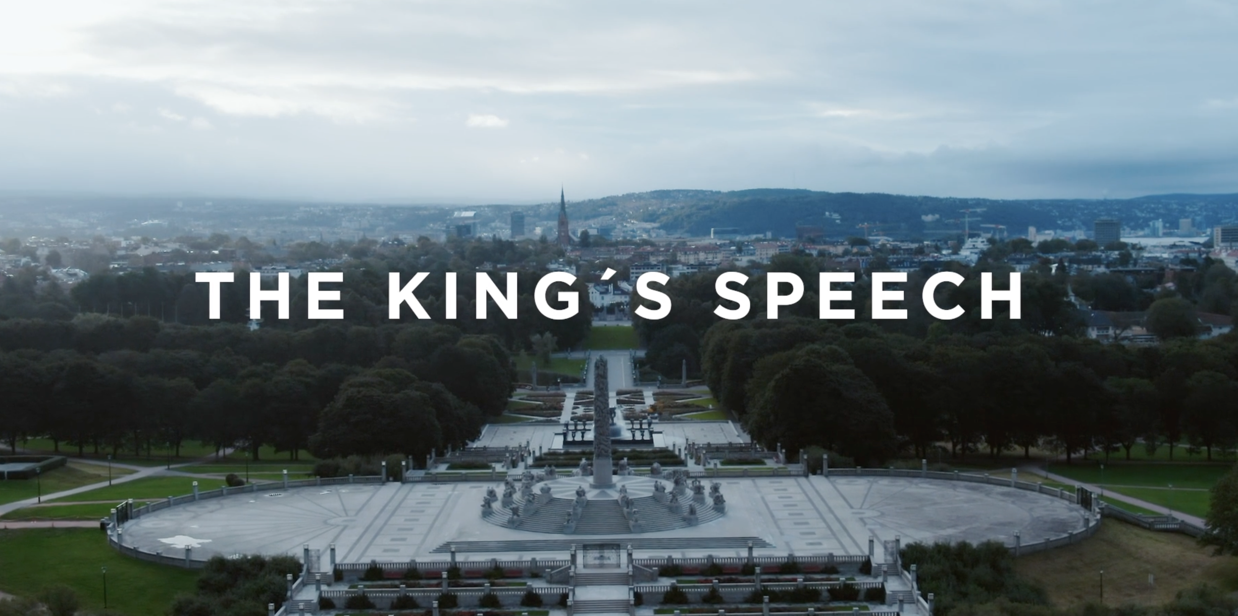 Aerial view of a large city park with a monument in the center, trees surrounding the park, and city buildings and hills in the background. Overlaid text reads "The King's Speech."