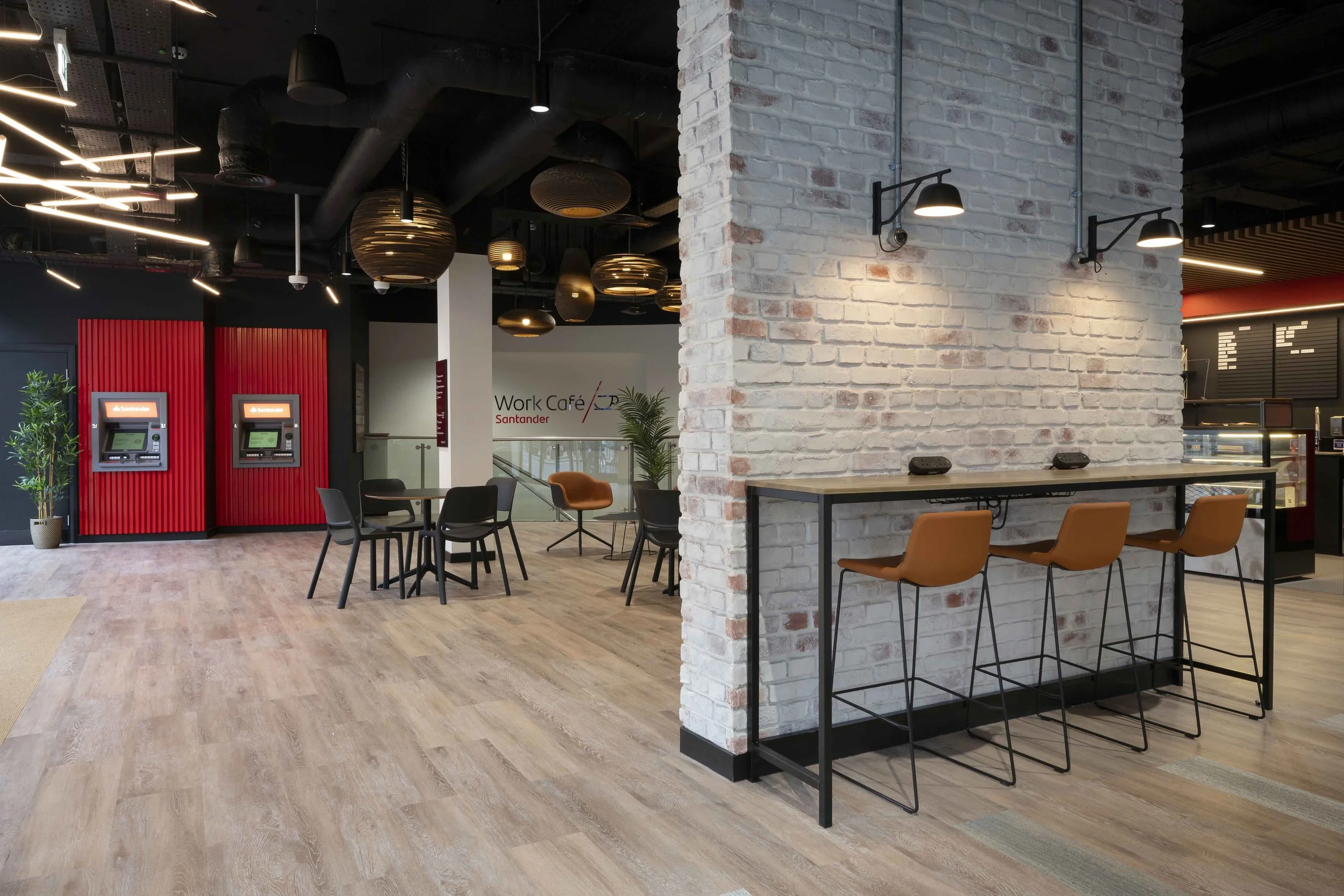 Interior of a modern coworking space with desks, chairs, brick walls, and decorative lighting fixtures.