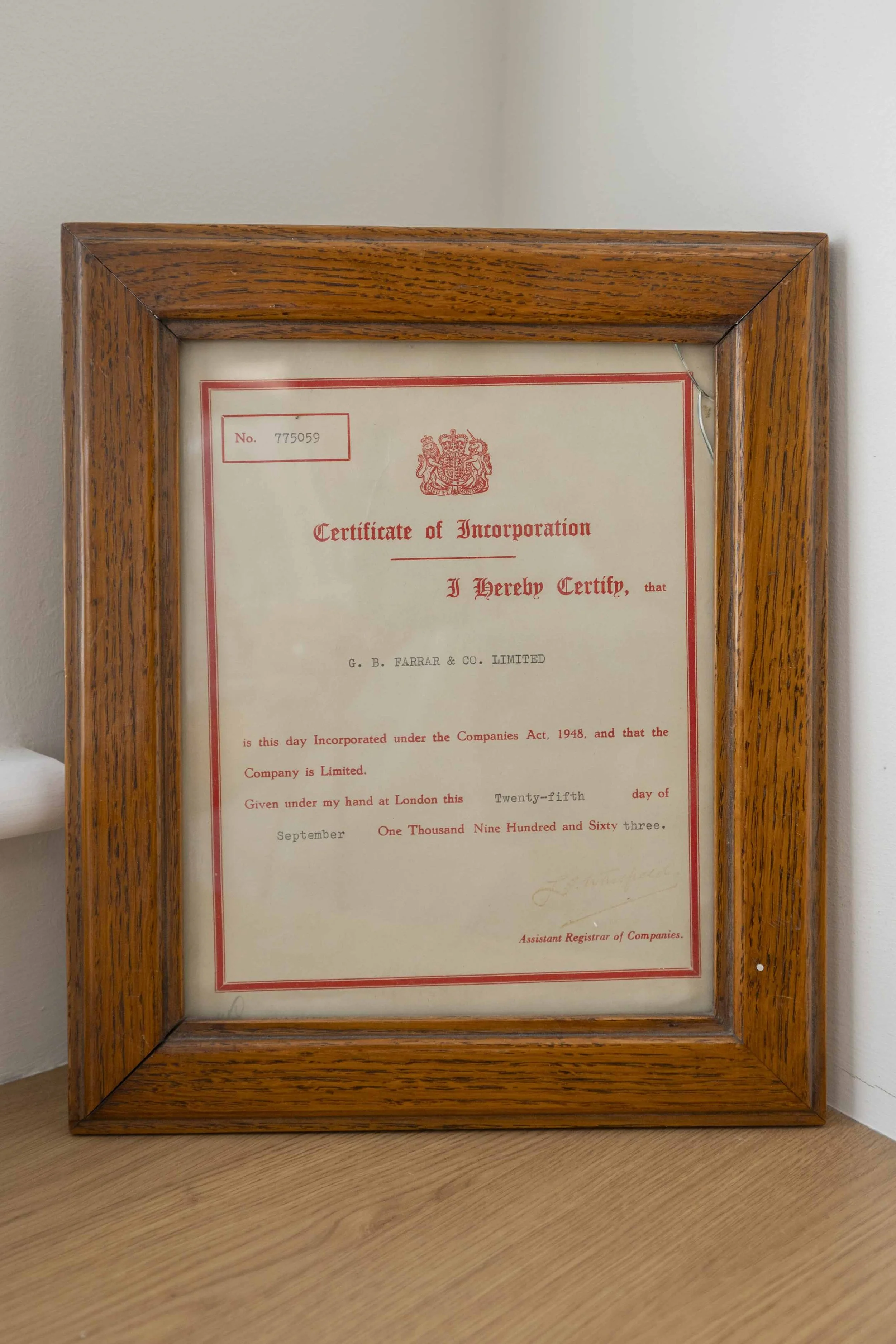A framed certificate of incorporation with a wooden border hanging on a light-colored wall.