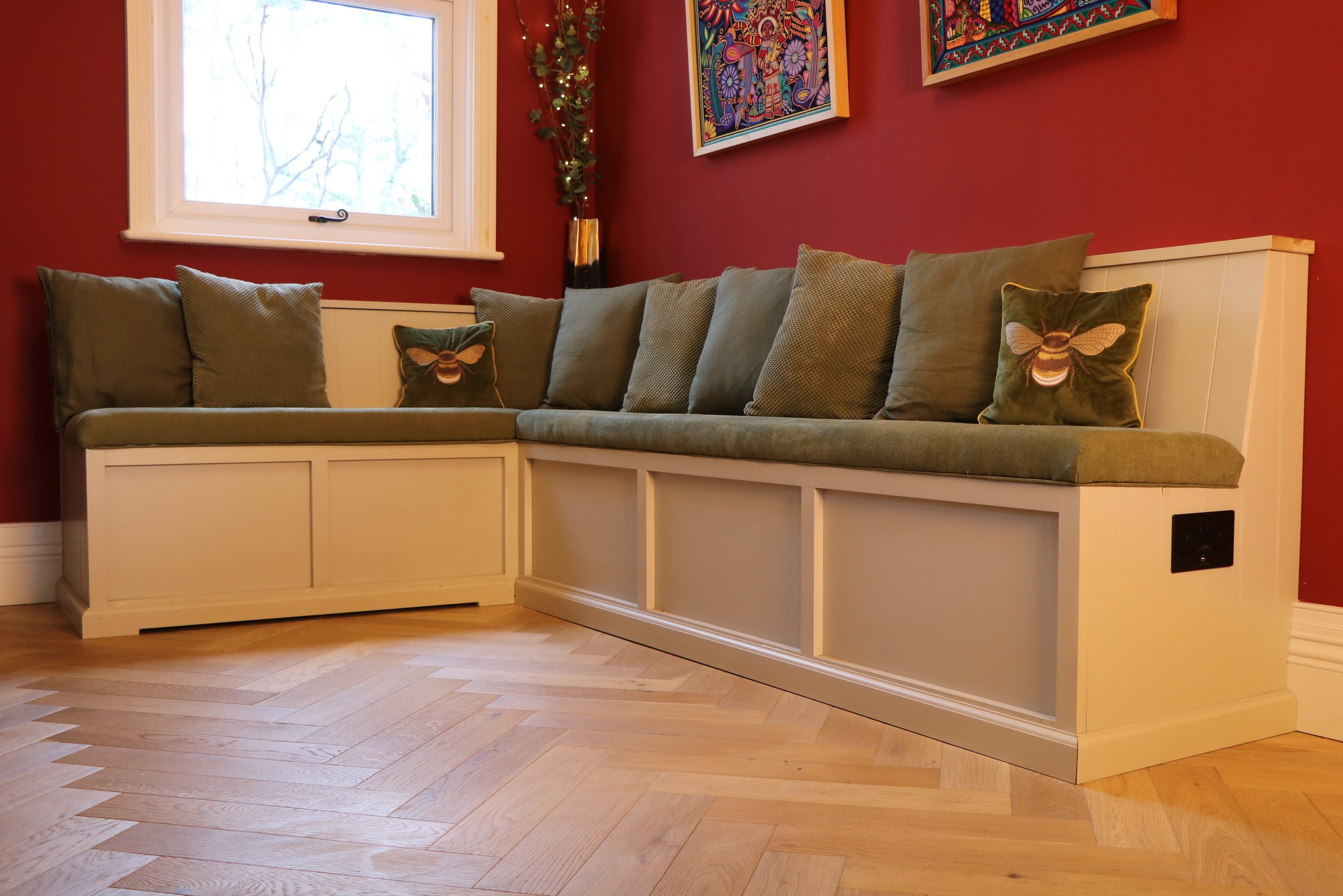 Bespoke built‑in corner bench hiding radiator, and storage underneath, handcrafted to create a cosy, inviting seating nook in a warm, characterful room.