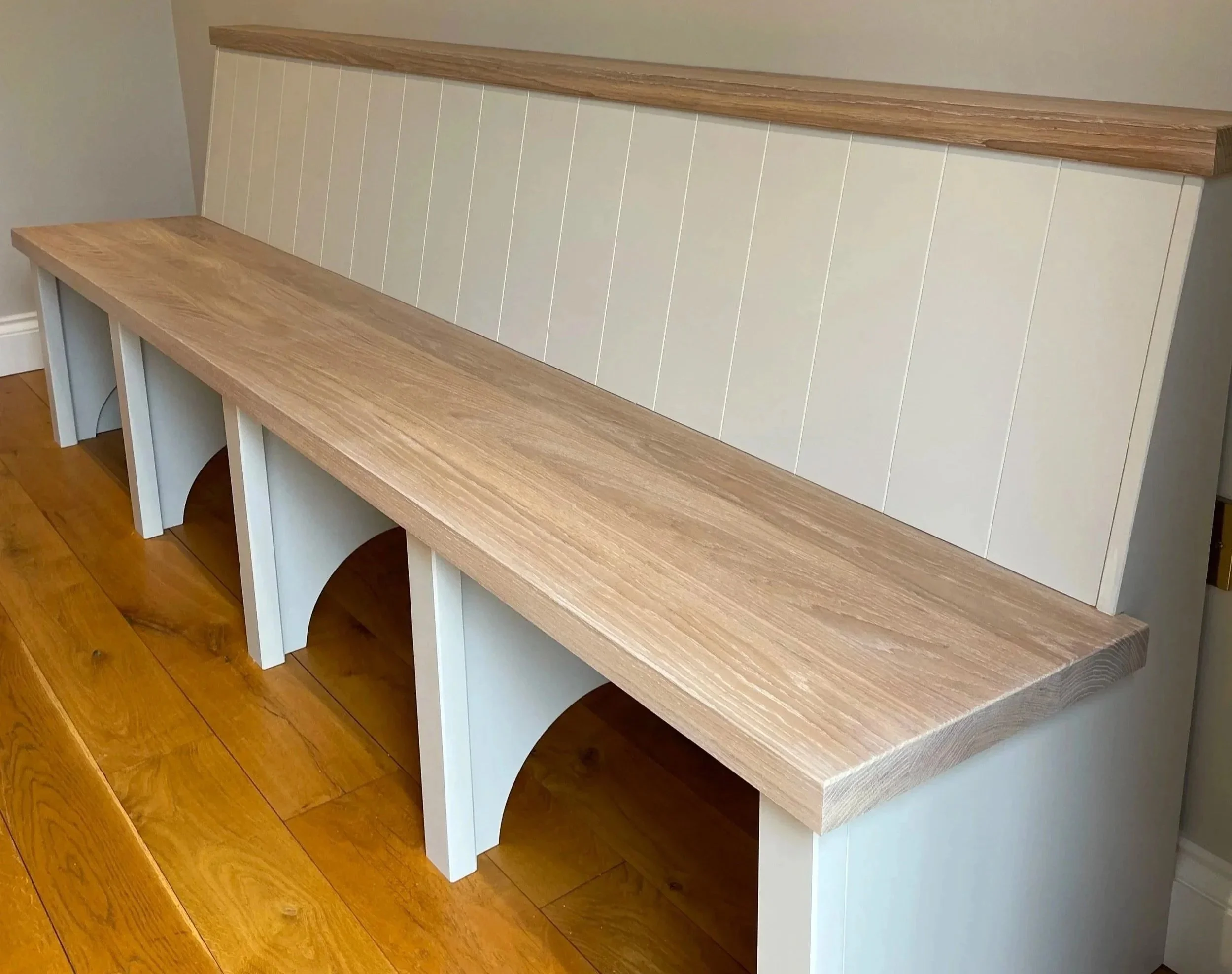 Bespoke built‑in hallway bench with a natural wood seat and white panelled base, handcrafted for neat, practical seating and storage.