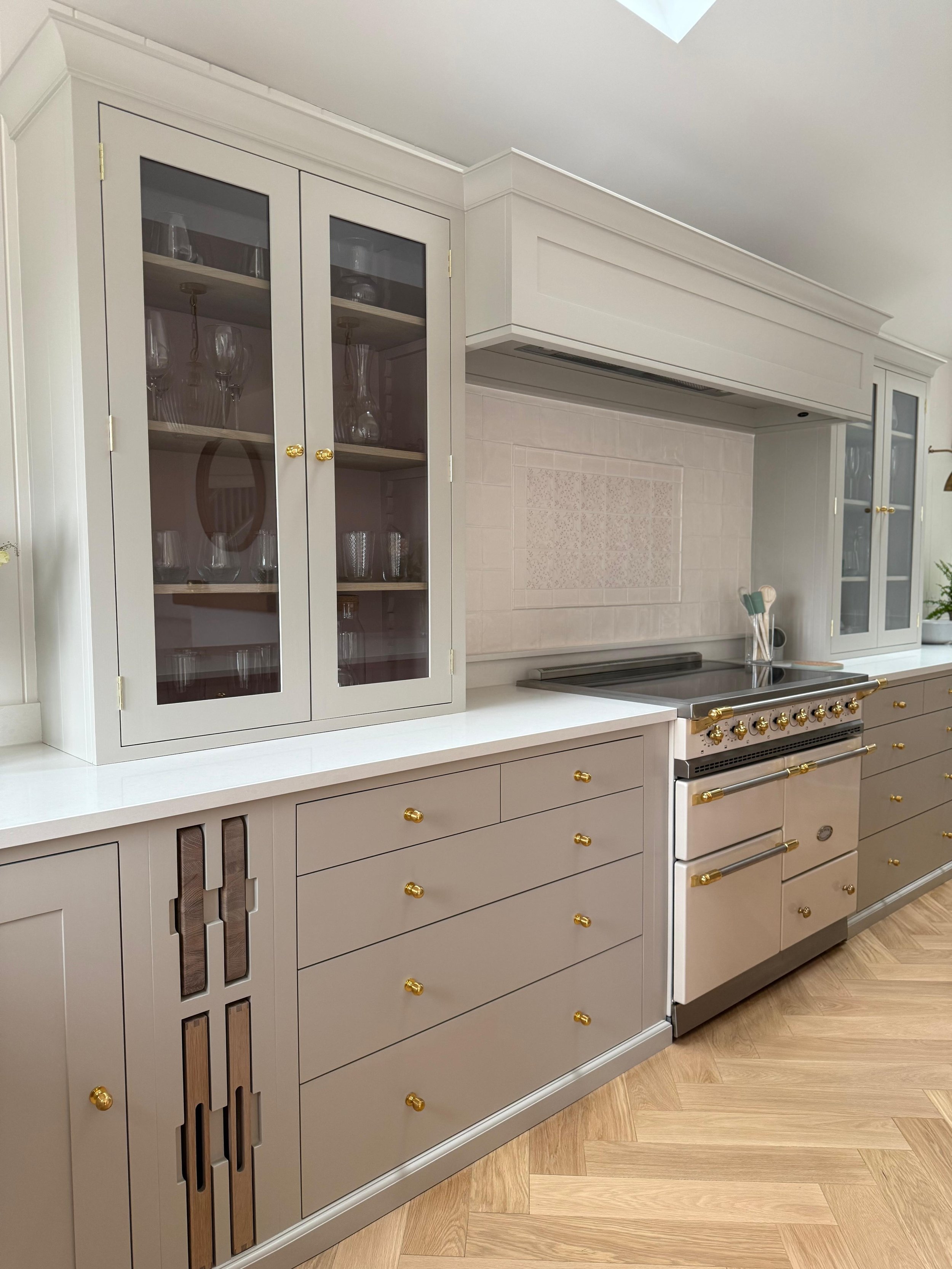Bespoke fitted kitchen with cream cabinetry, brass details and a counter‑top cabinet for extra storage, keeping everyday items neat beside the range cooker.