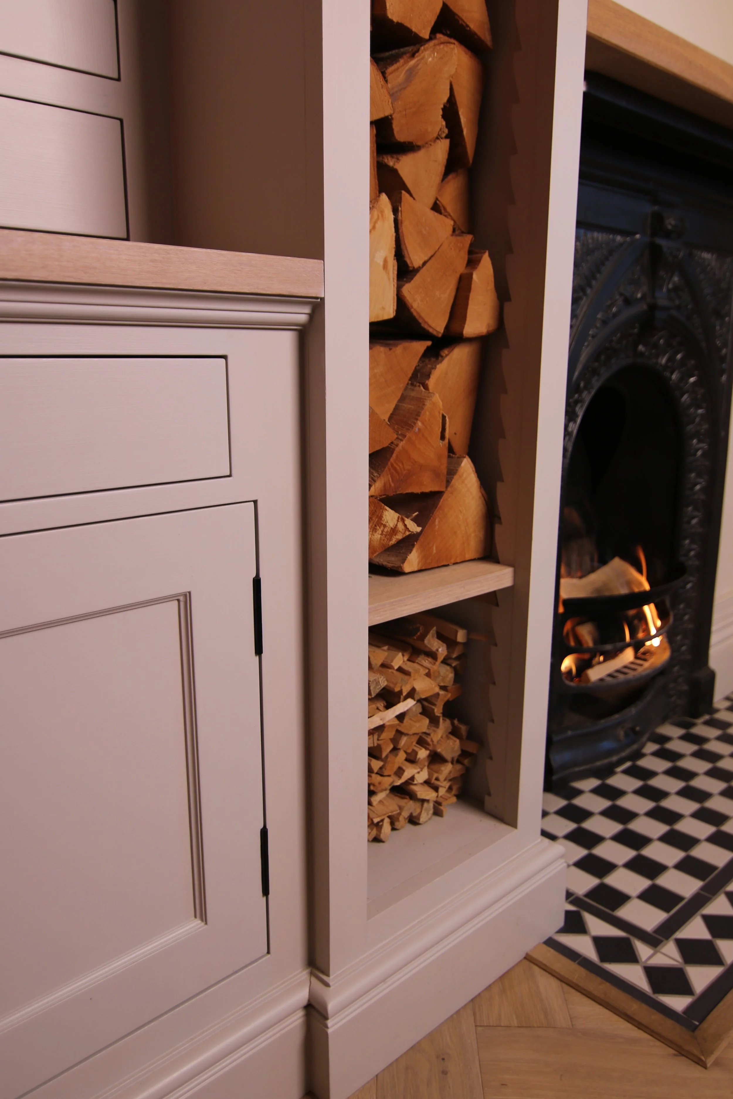Close up of fitted log store with a section for kindling either side of a fireplace. Traditional detail without being fussy creating a cosy timeless atmosphere. 