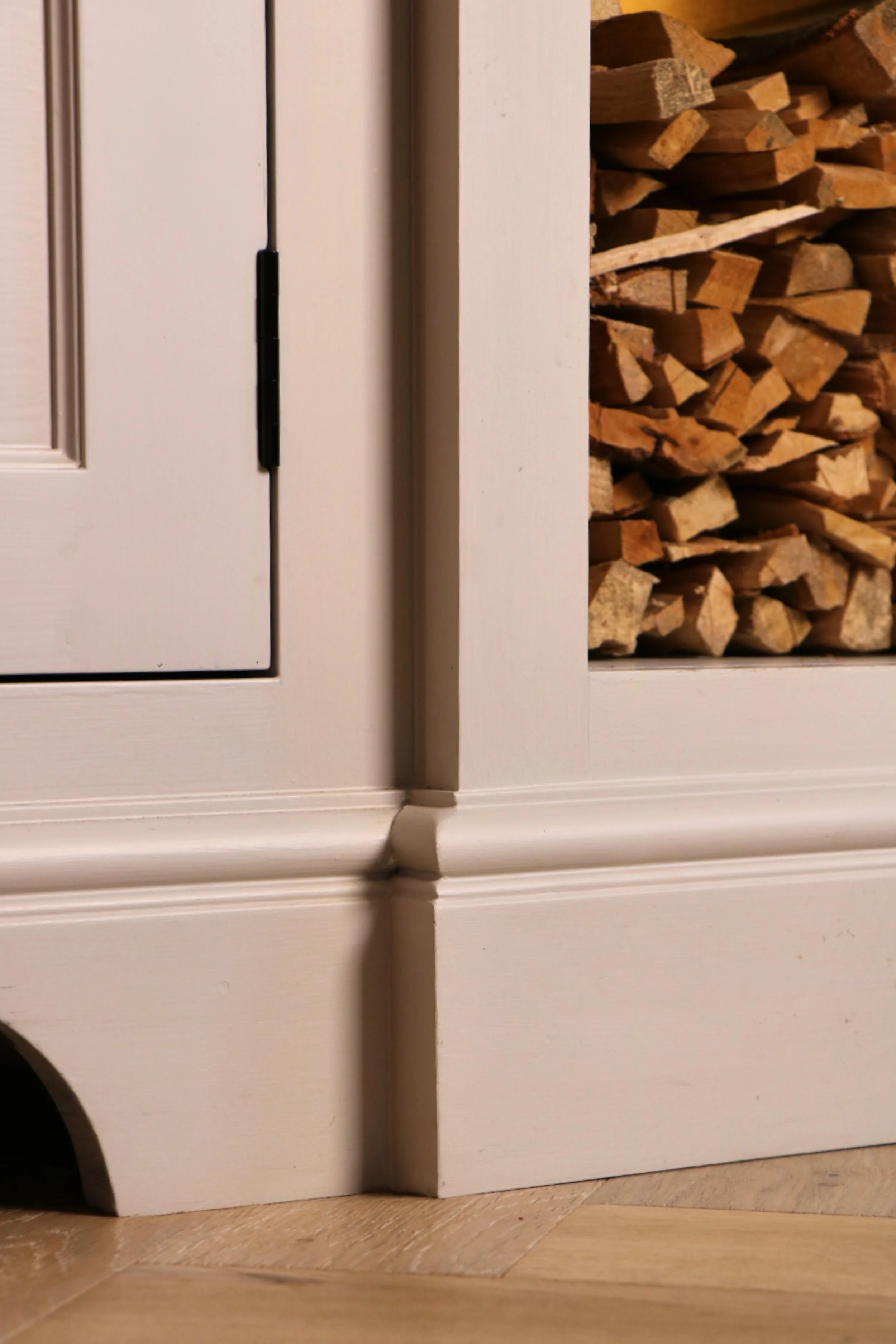 Close up image of detailed skirting around a fitted log store and AV unit showing calm and classic detail.
